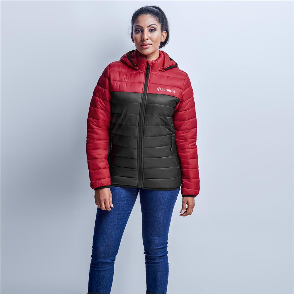 Woman wearing a red and black puffer jacket on a light gray background