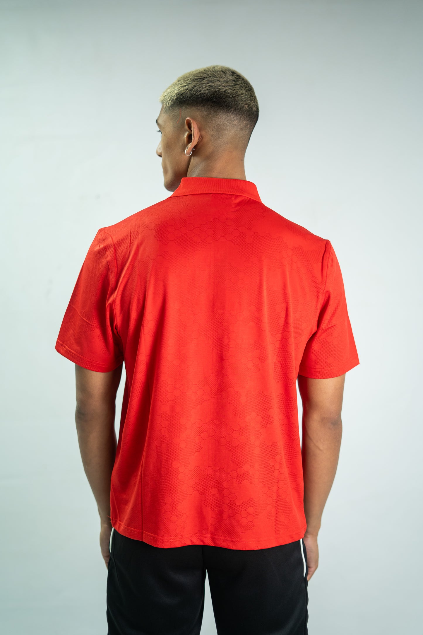 Person wearing a red polo shirt on a plain background
