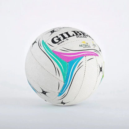 A white Gilbert Pulse netball ball with black text and colorful pink, teal, and blue graphic accents, photographed on a light gray background.


