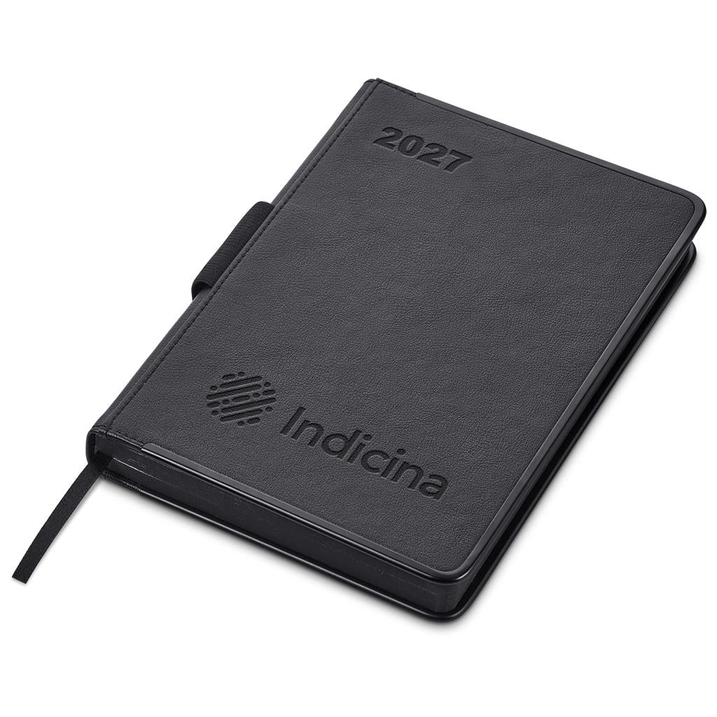 A black textured 2027 daily planner by Indicina, shown closed at an angle on a white background. The cover features an embossed '2027' in the top right corner and the 'Indicina' brand logo with a striped circle design in the bottom left.

