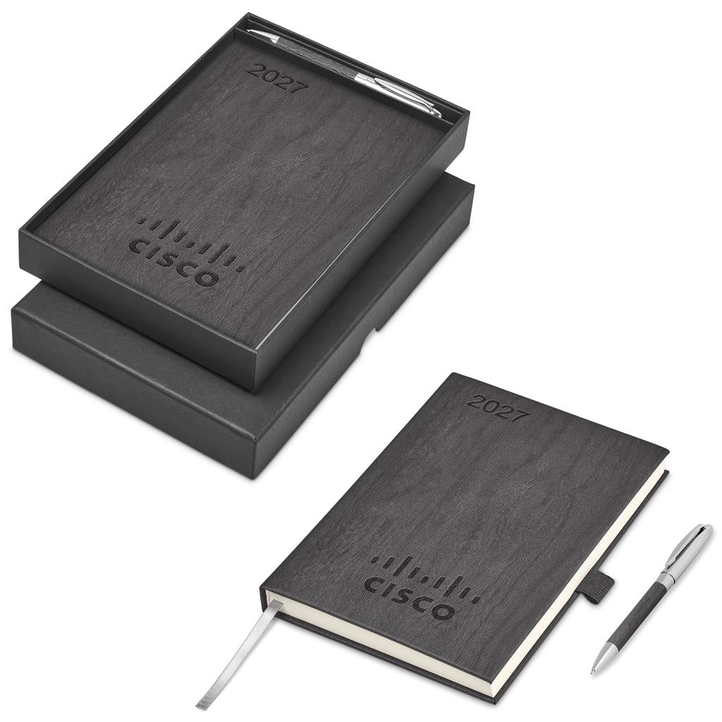 A 2027 planner set shown in both open and closed states, featuring a dark wood-grain textured cover, a silver pen, and a white ribbon bookmark, alongside its black presentation box.

