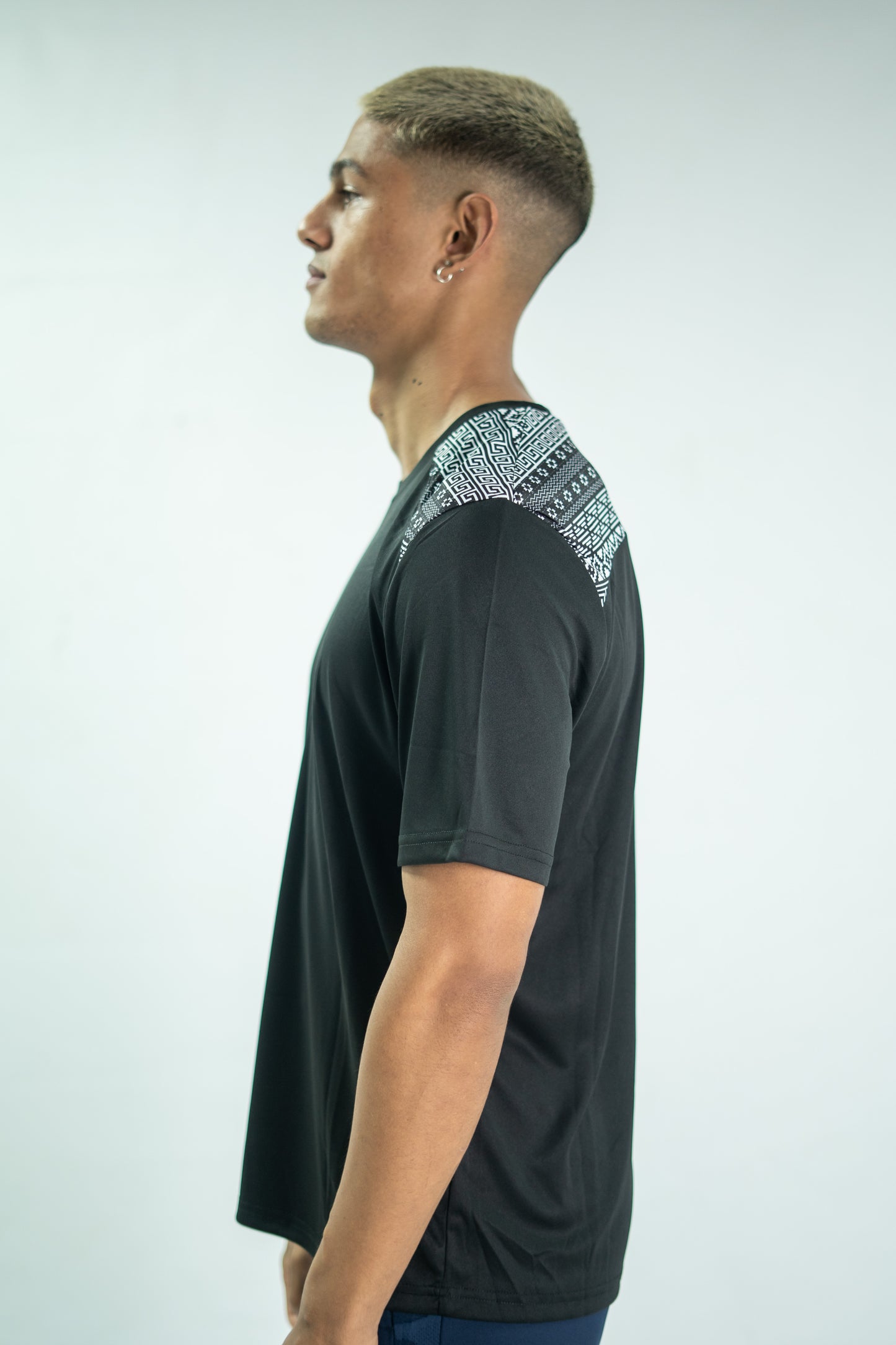 Man wearing a black t-shirt with patterned shoulders against a white background

