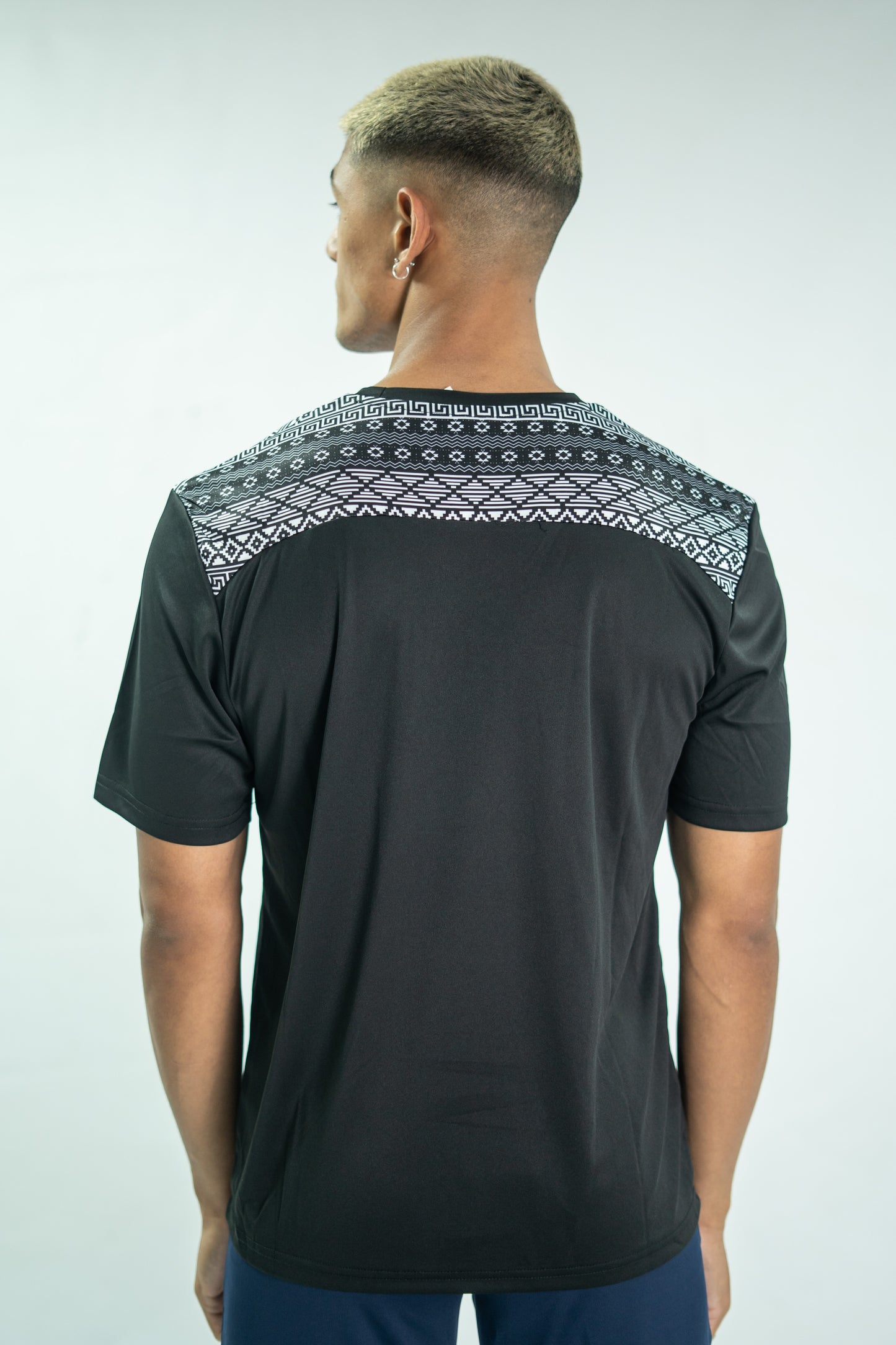 Man wearing a black t-shirt with patterned shoulders on a white background

