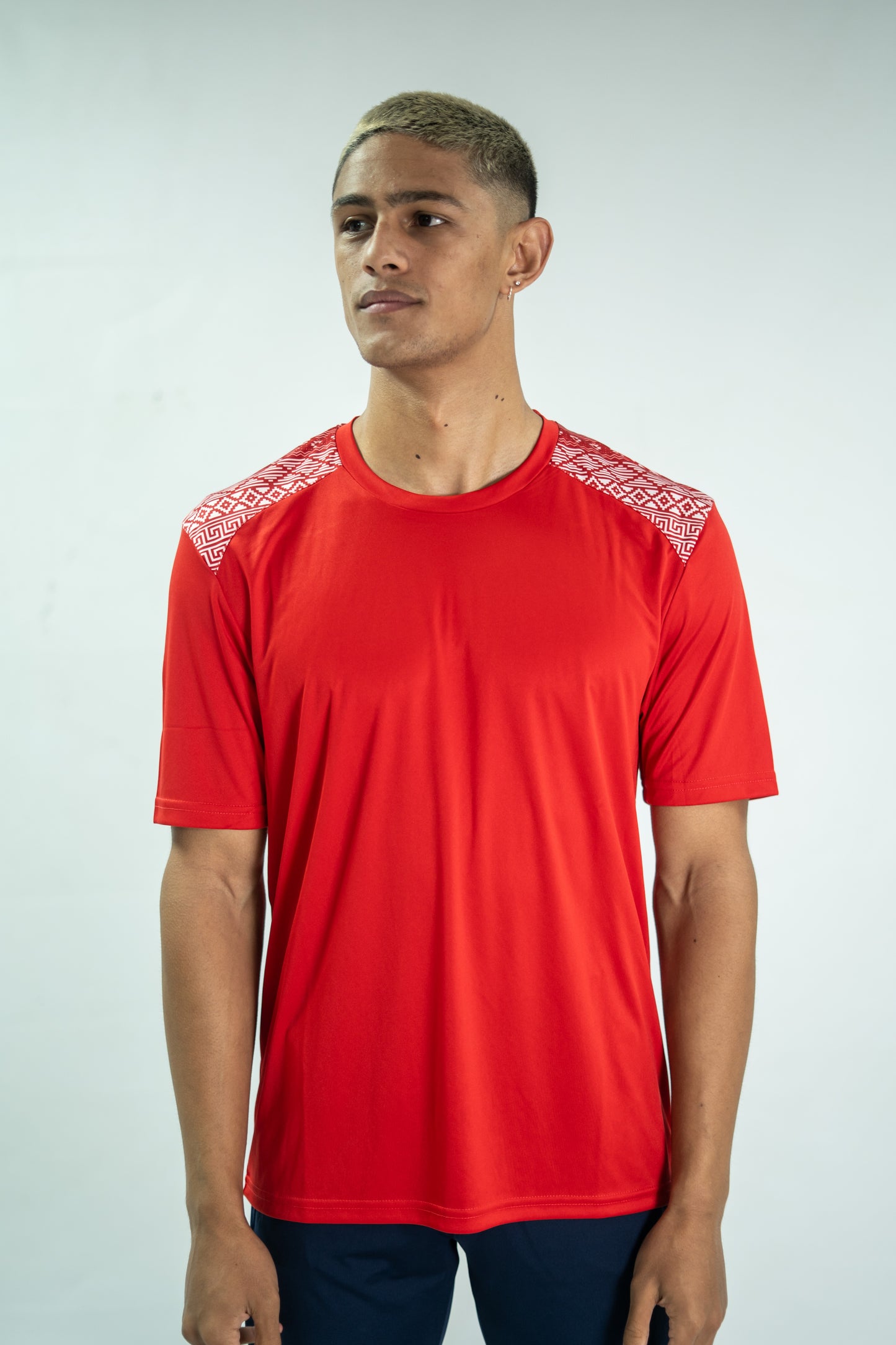 Person wearing a red sports jersey with white patterns on a plain background

