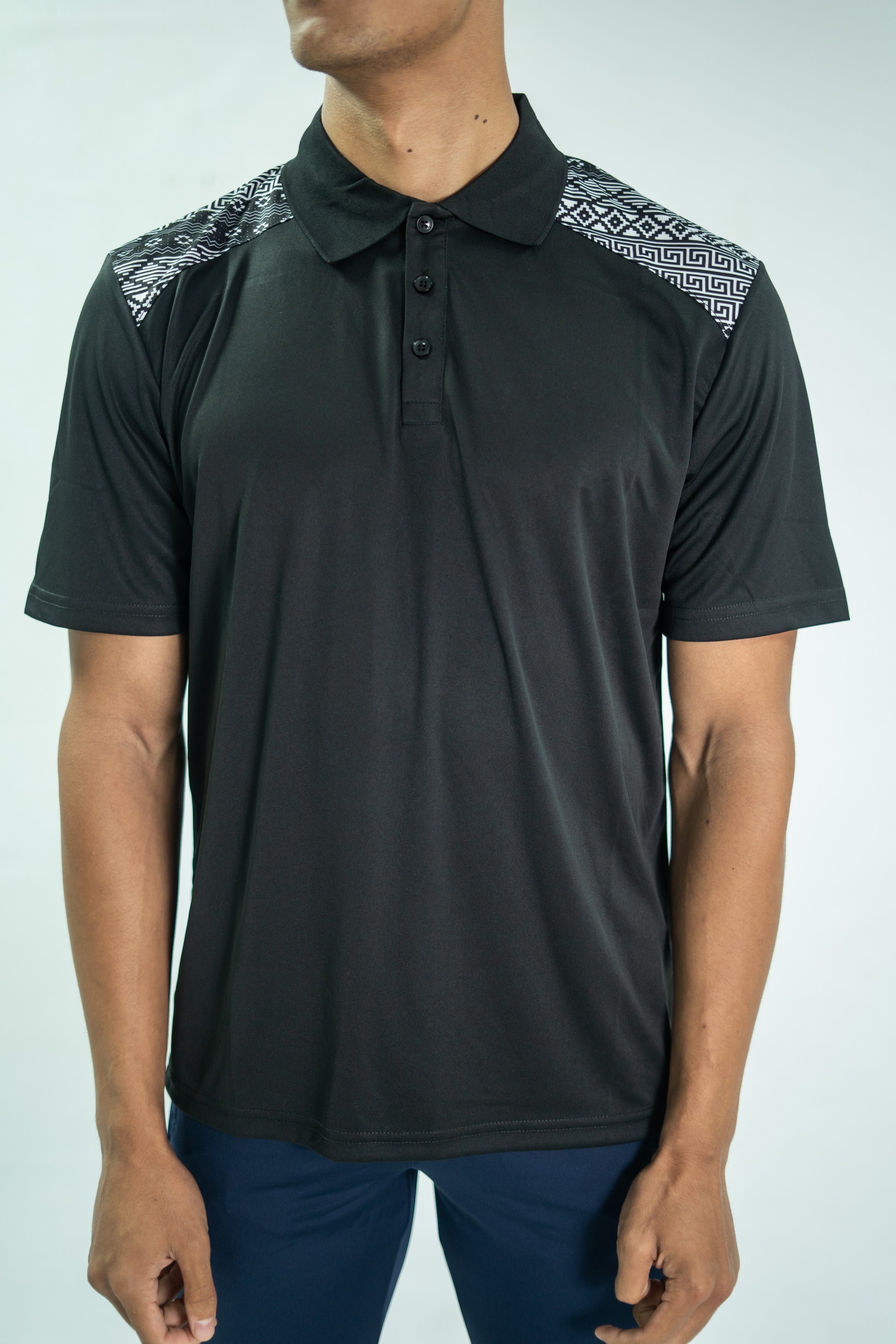 Black polo shirt with patterned shoulders worn by a person on a white background

