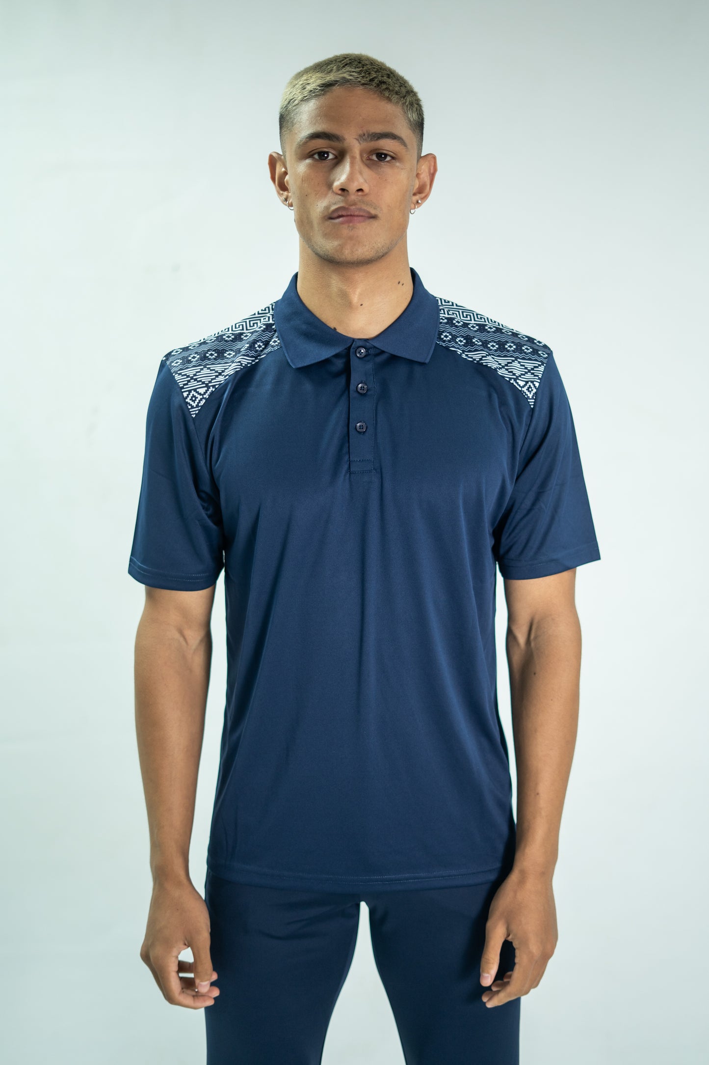 Man wearing a blue Adidas polo shirt with patterned shoulders on a white background

