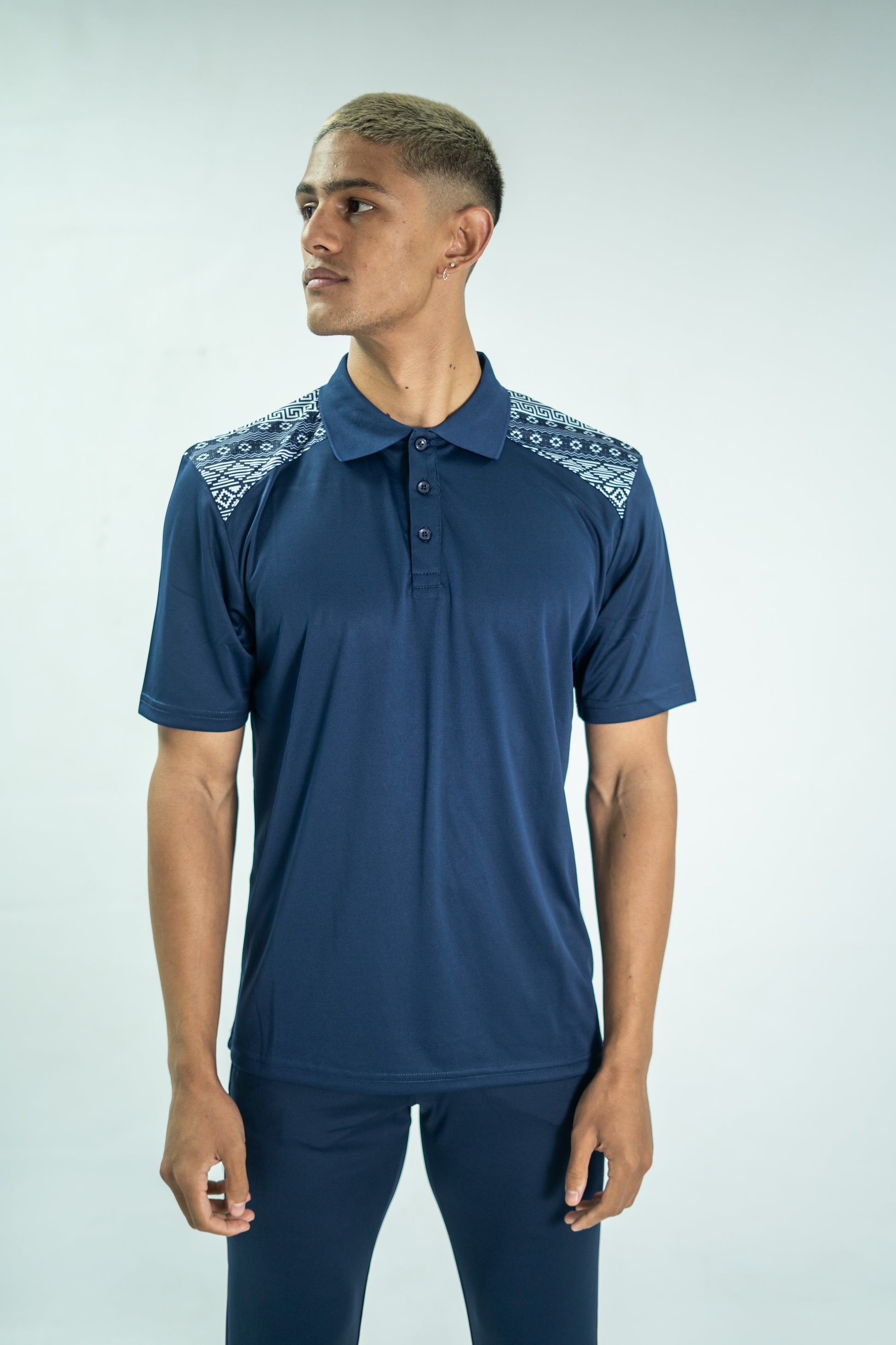 Man wearing a navy blue polo shirt with lace details on a light gray background


