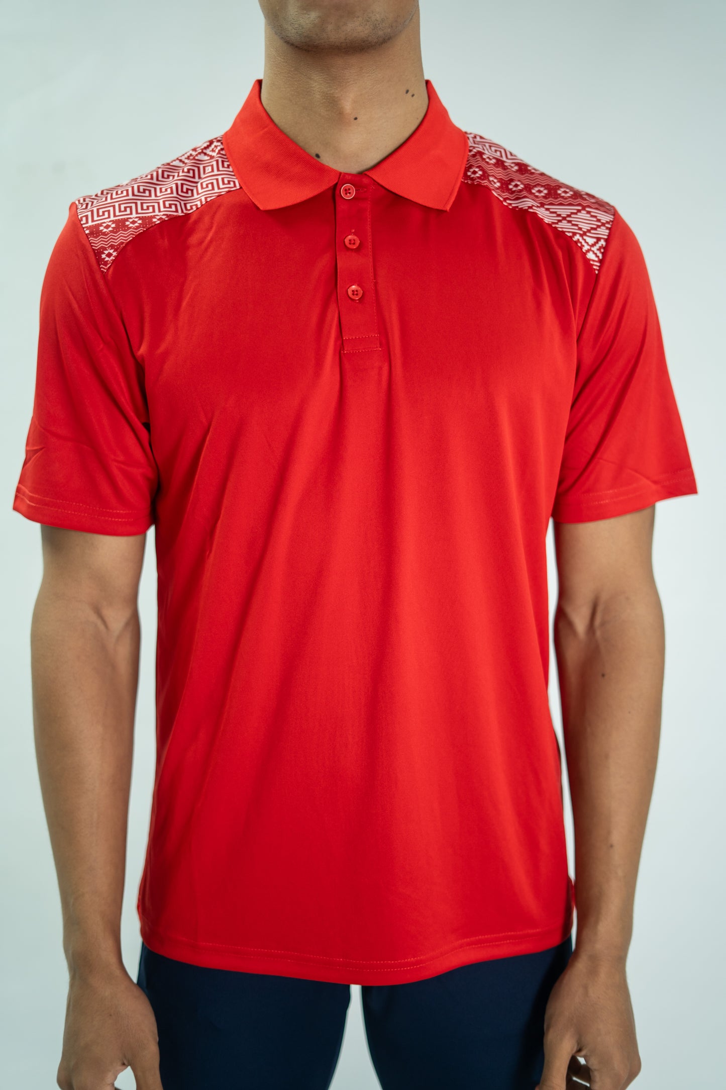 Red polo shirt with white patterns on shoulders against a plain background

