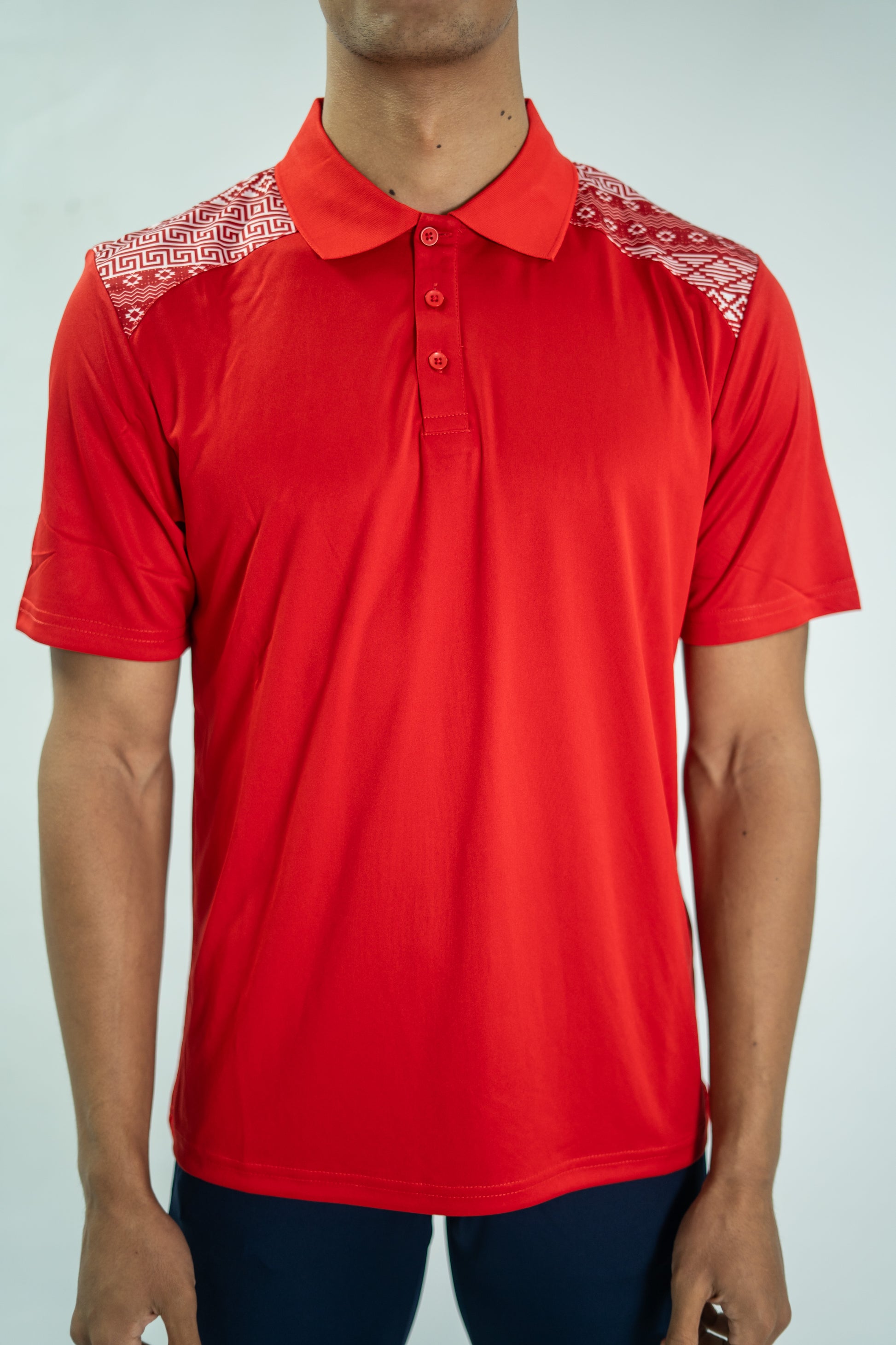Red polo shirt with white patterns on shoulders against a plain background

