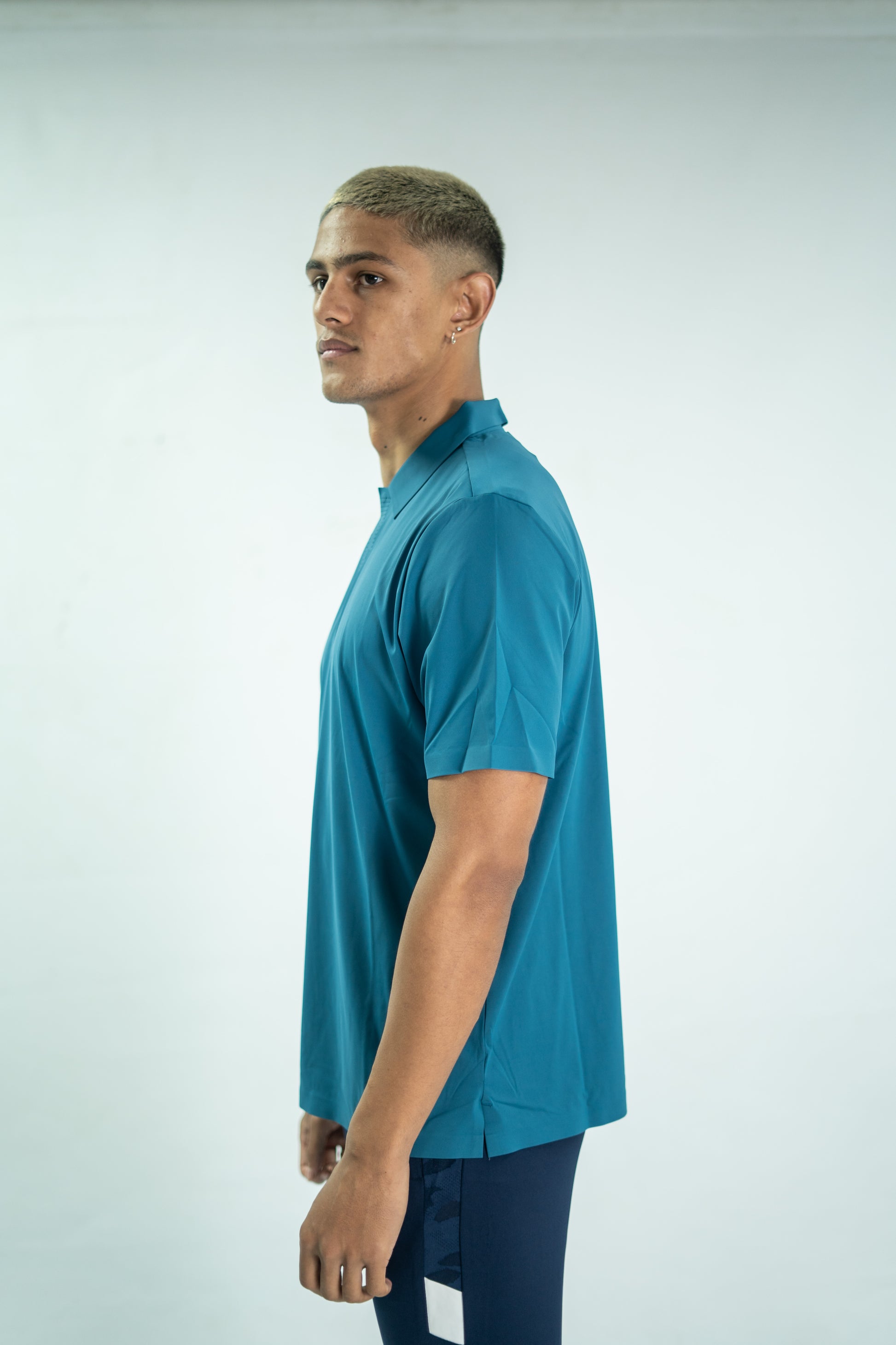 Man wearing a teal polo shirt on a light gray background

