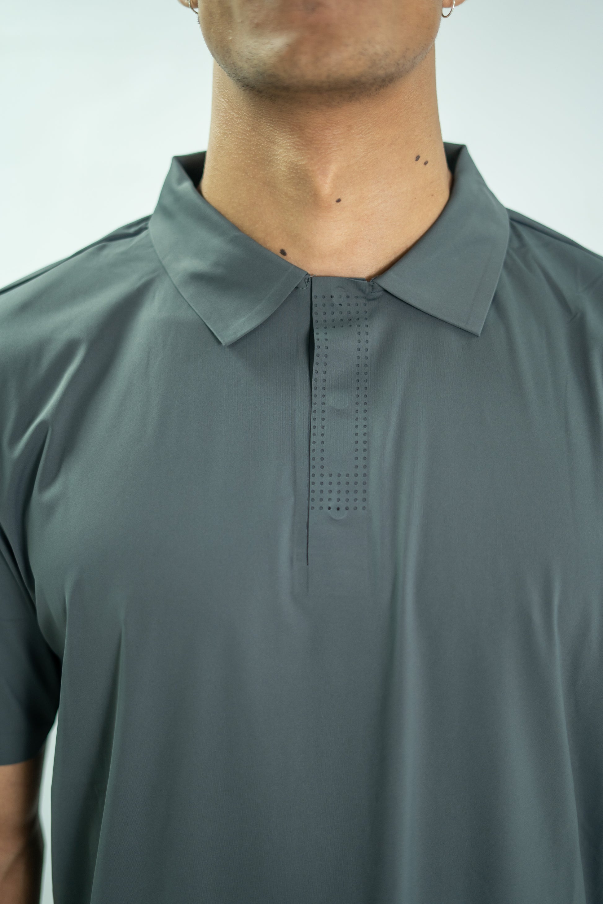 Gray polo shirt worn by a person on a light gray background

