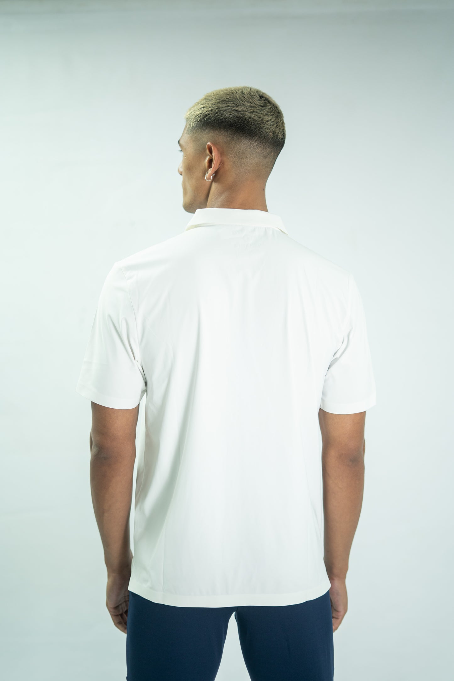 Man wearing a white polo shirt on a plain background

