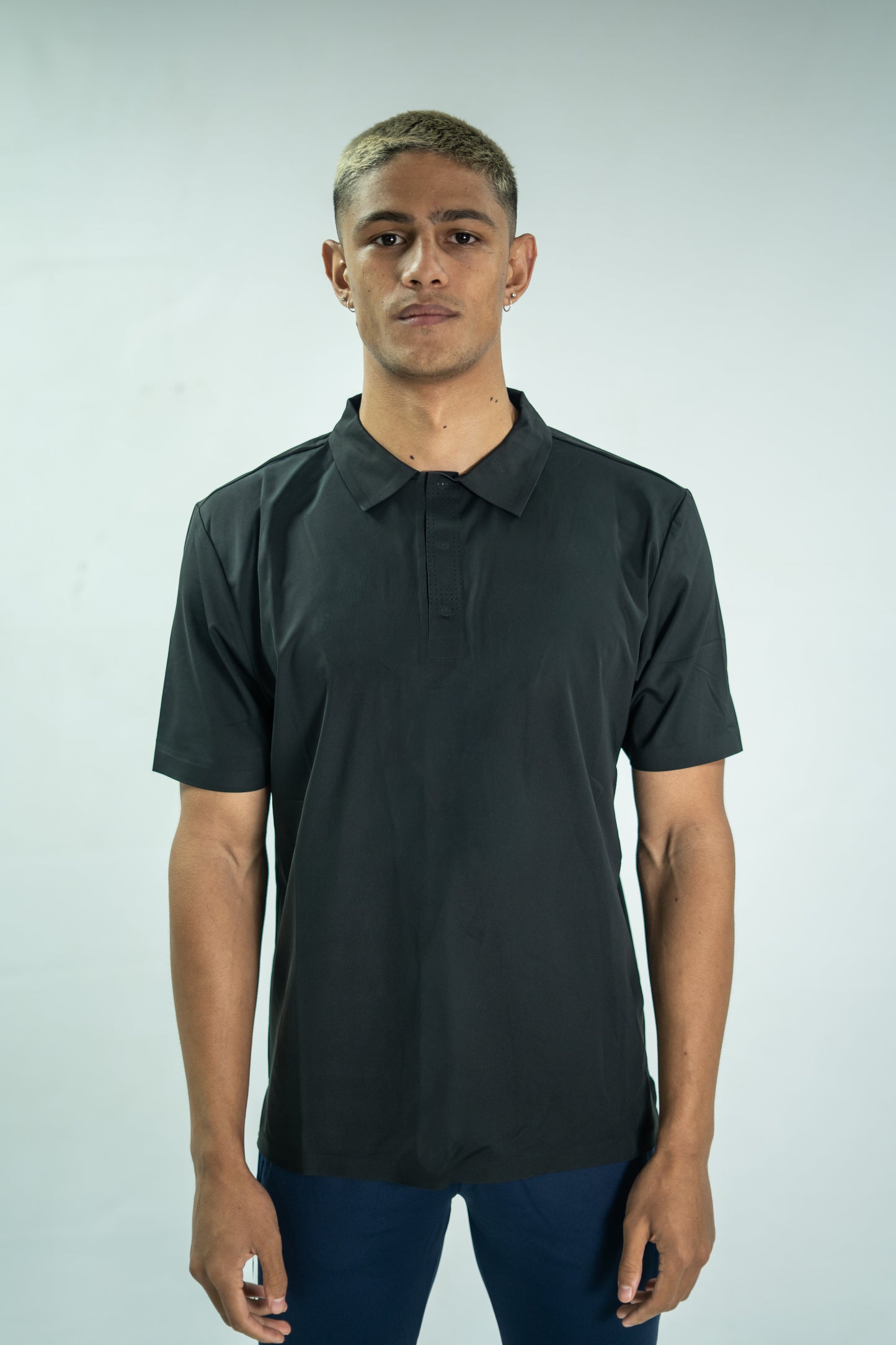 Man wearing a black polo shirt against a white background

