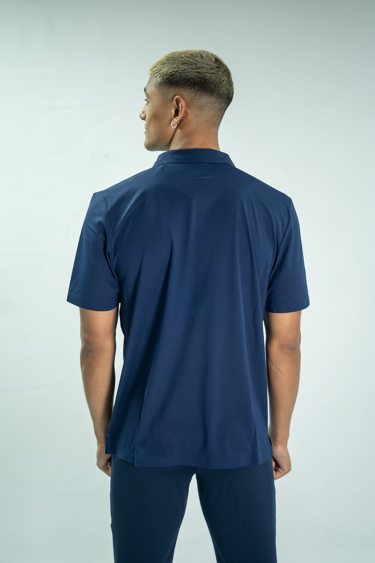 Man wearing a navy blue polo shirt and pants on a light gray background

