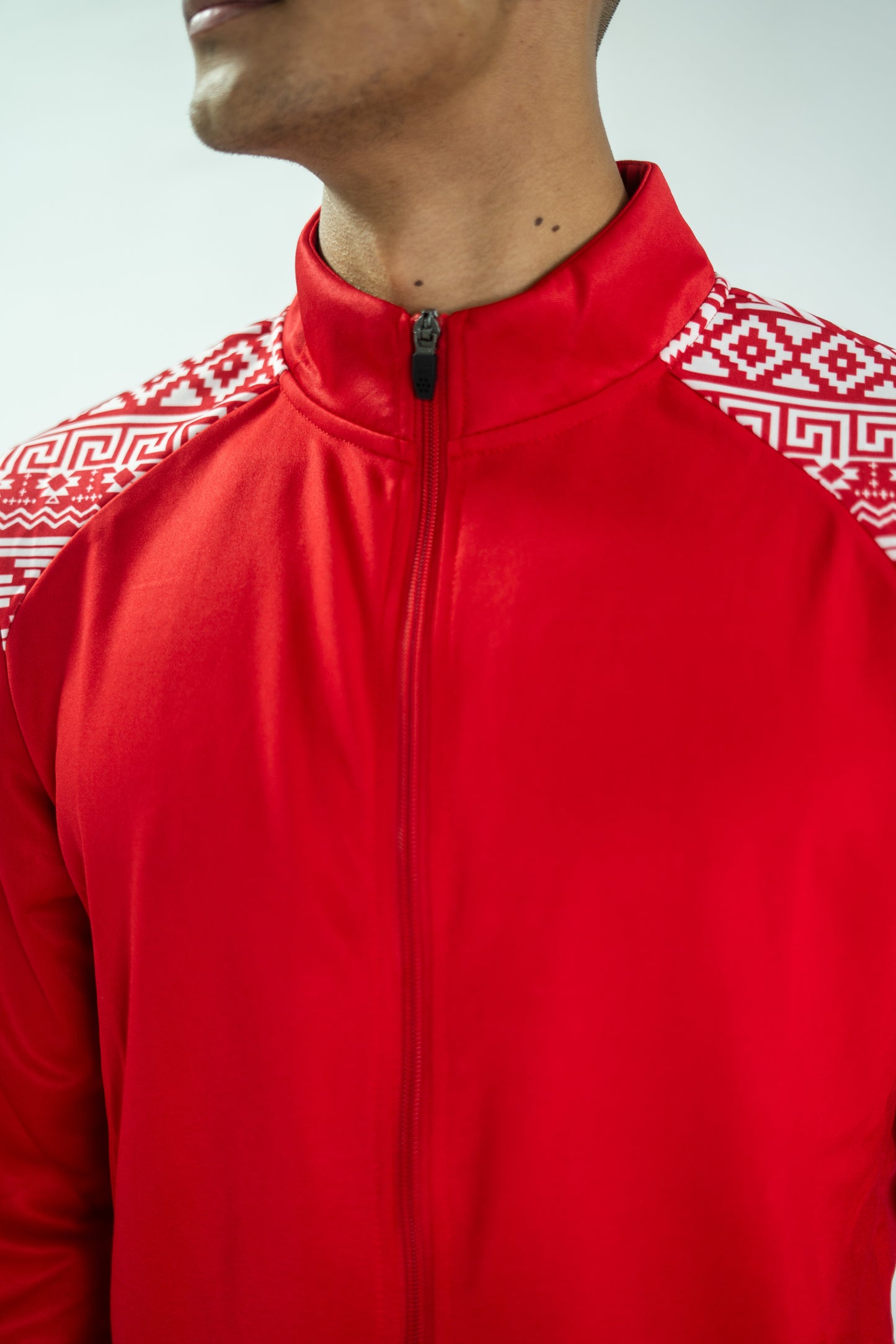 Red jacket with white geometric patterns on sleeves and collar, worn by a person.

