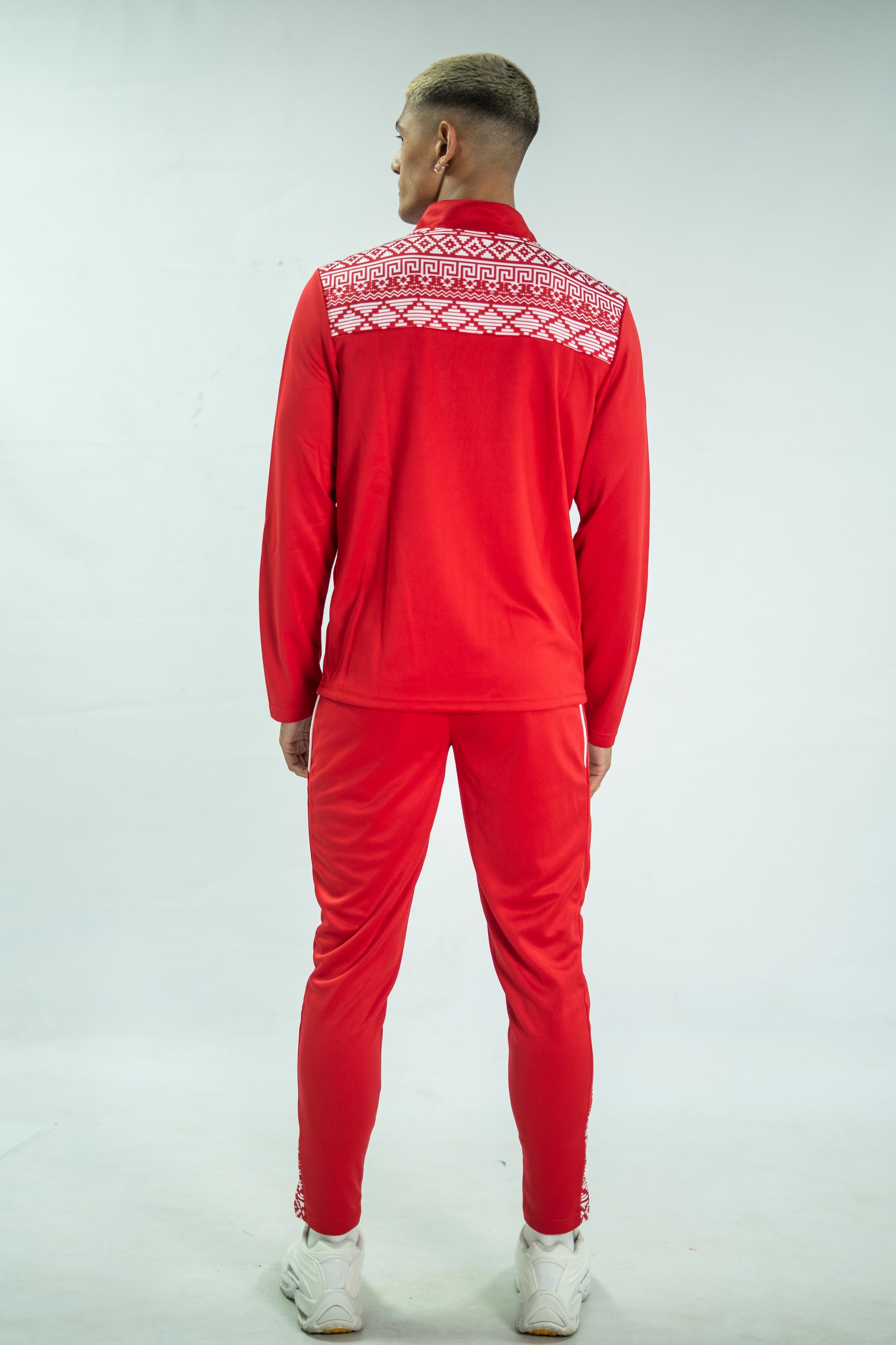 Person wearing a red tracksuit with white patterned collar on a light gray background

