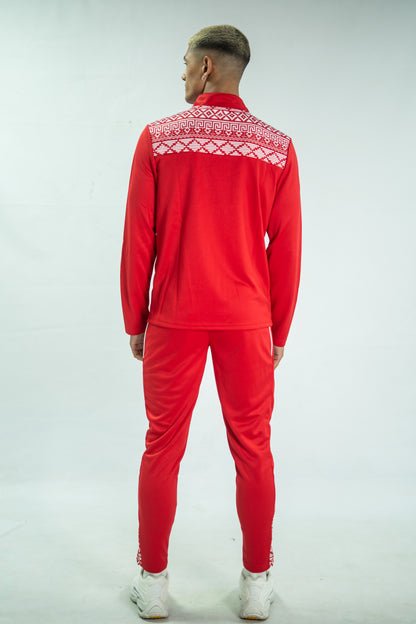 Person wearing a red tracksuit with white patterned collar on a light gray background

