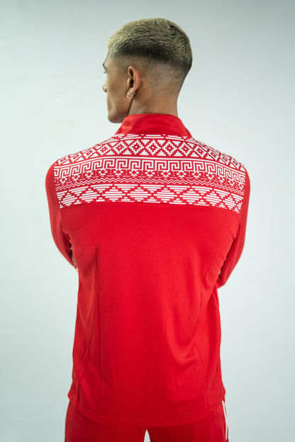 Person wearing a red tracksuit with white patterned shoulders on a light gray background

