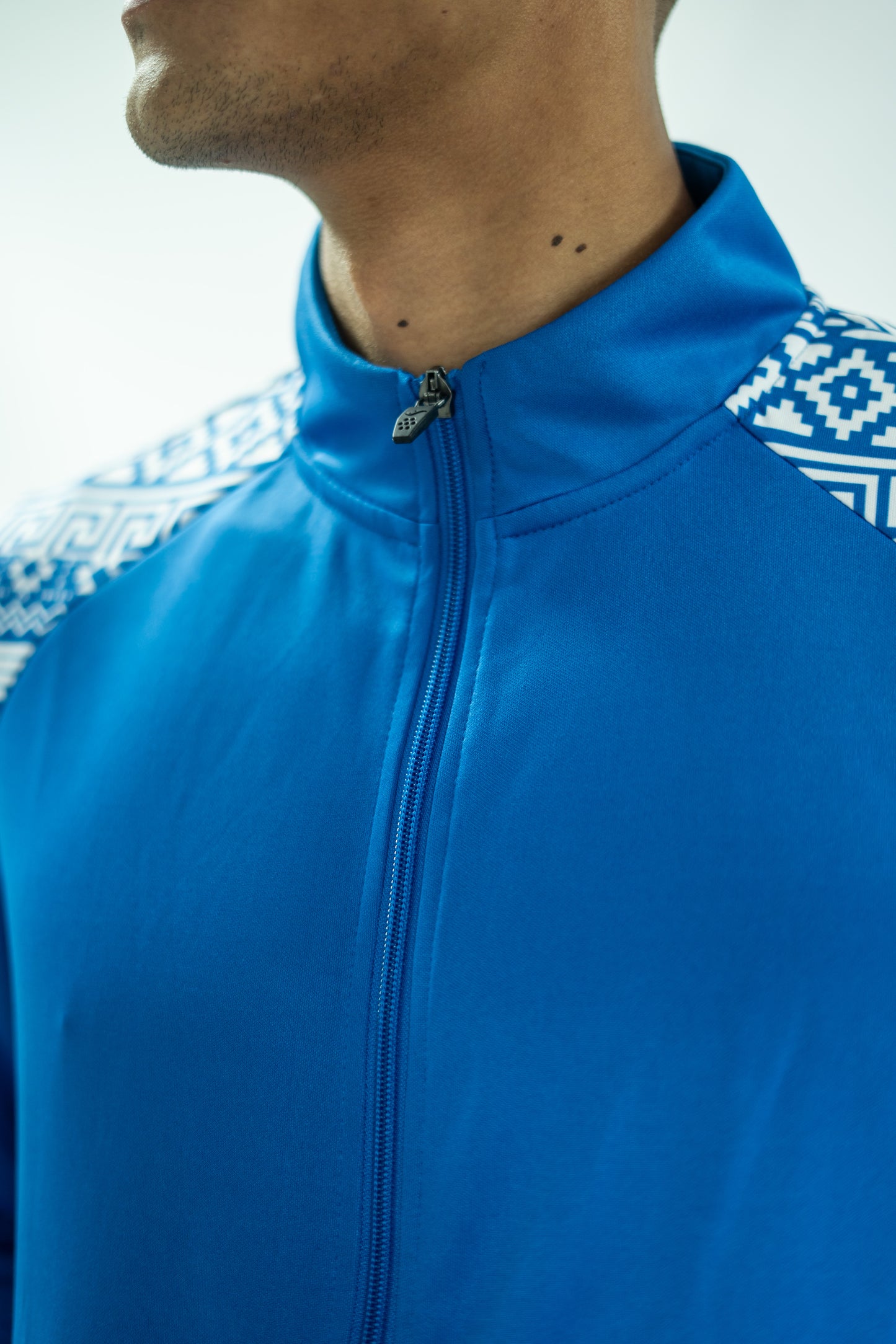 Blue jacket with patterned shoulders on a neutral background

