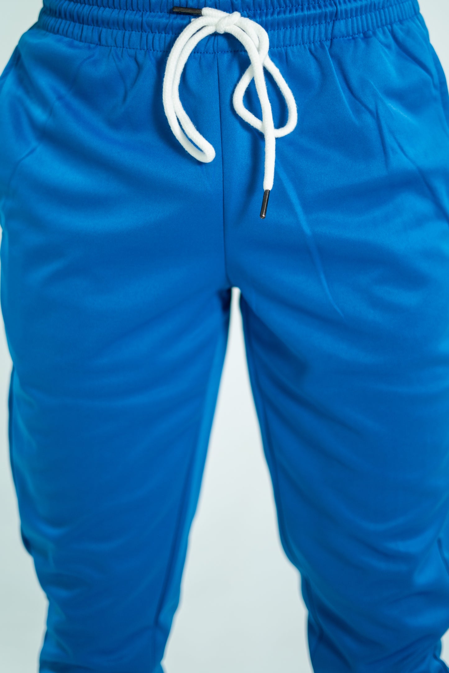 Blue pants with a white drawstring on a light gray background

