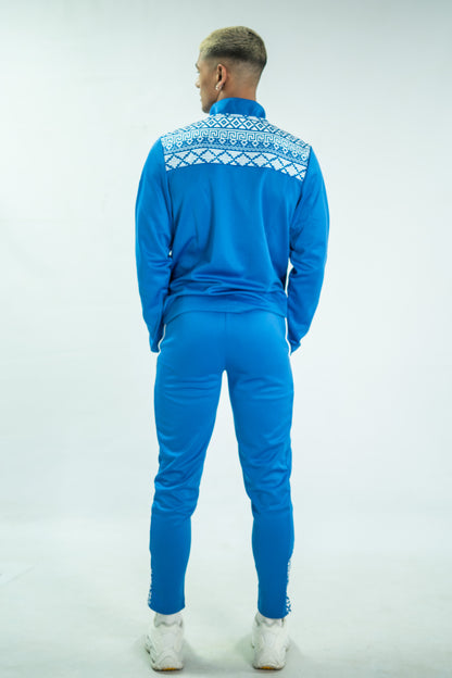 Person wearing a blue tracksuit with white patterns on a light gray background

