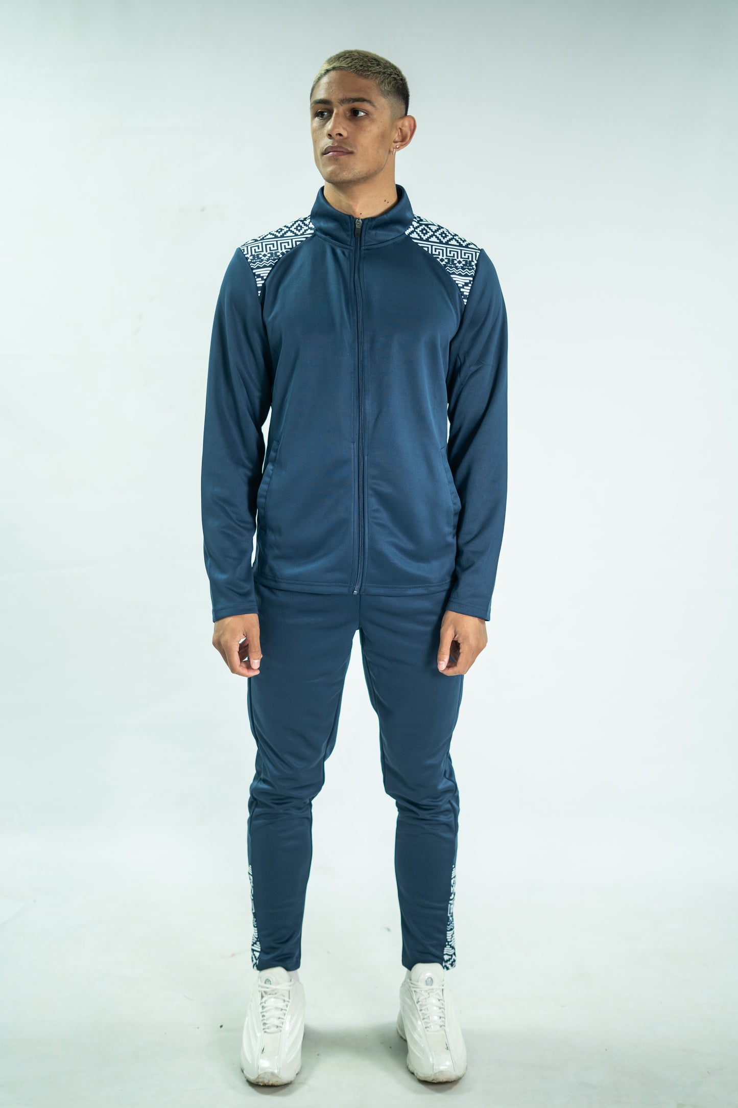 Man wearing a blue tracksuit with white accents on a light gray background

