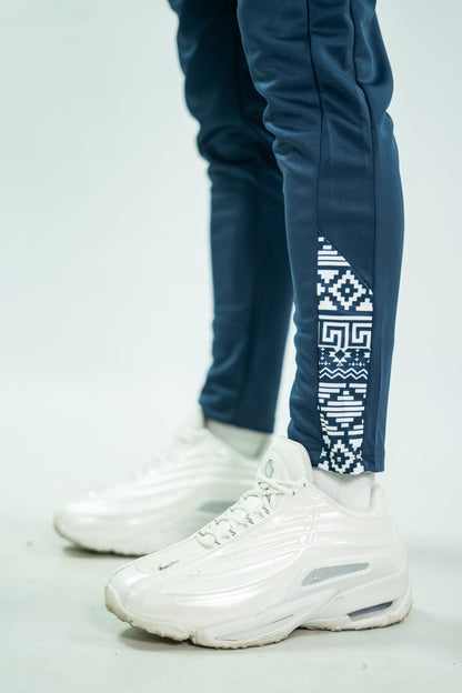 White sneakers with a person wearing blue pants with a geometric pattern on a light gray background

