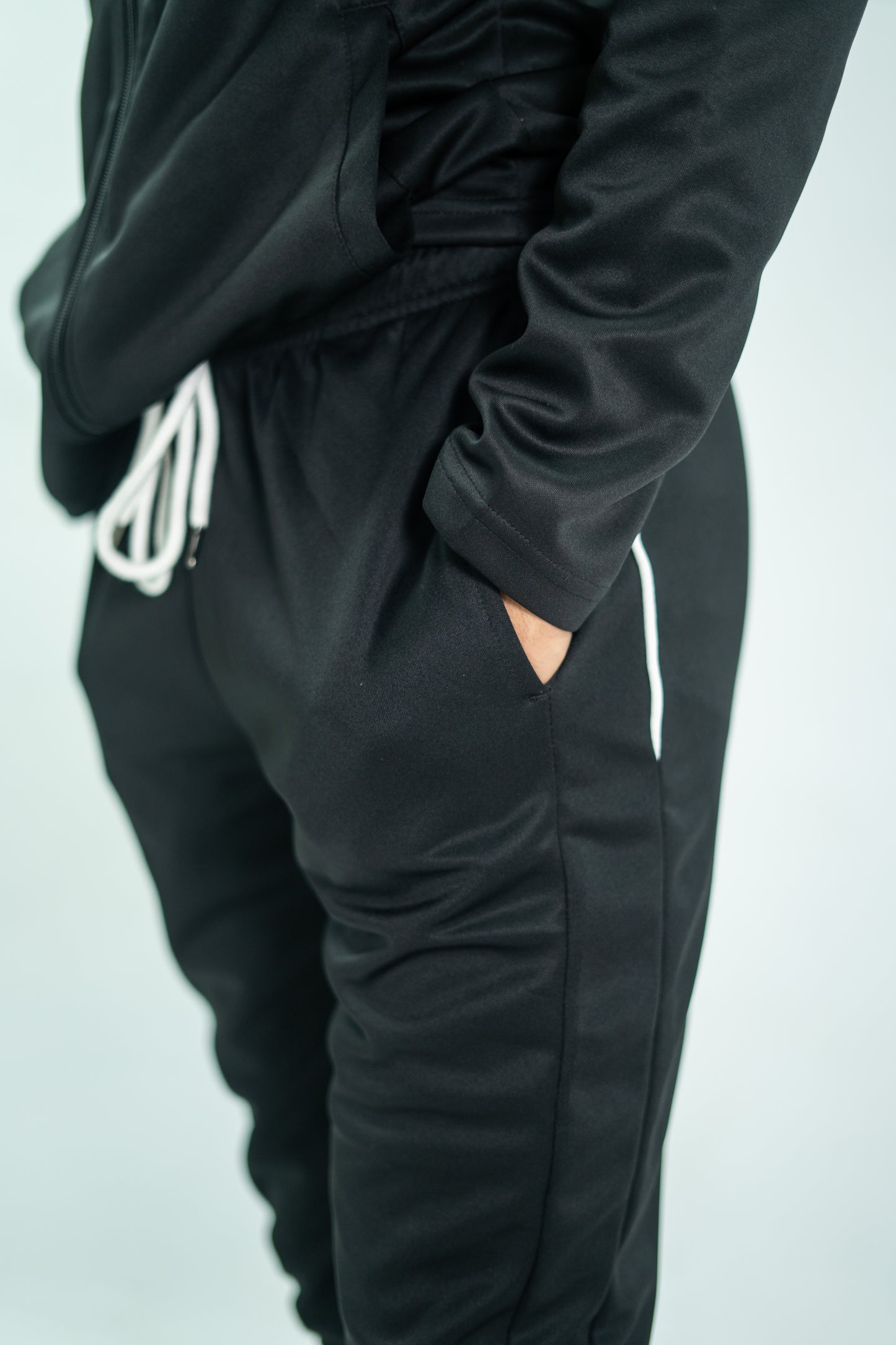 Black tracksuit with white logo on a light gray background

