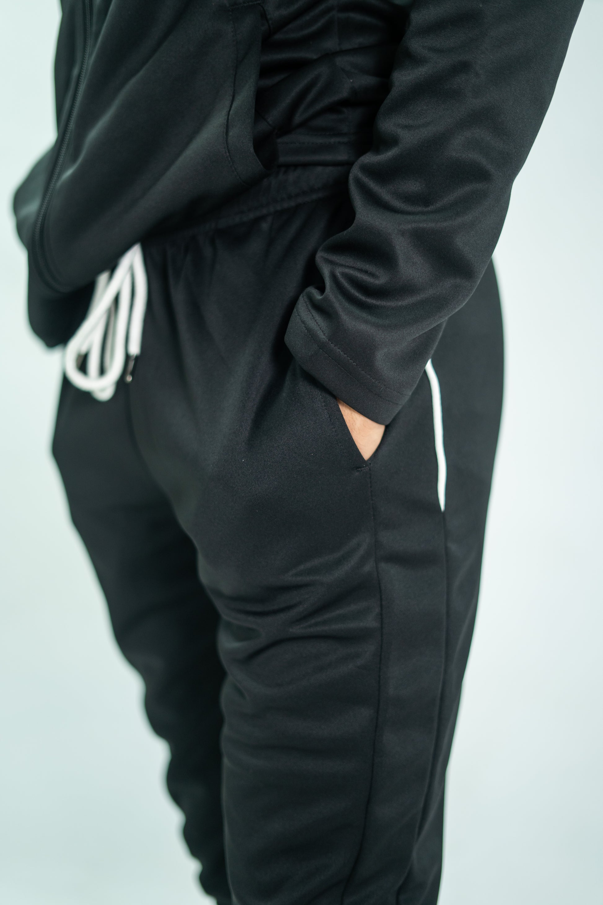 Black tracksuit with white logo on a light gray background

