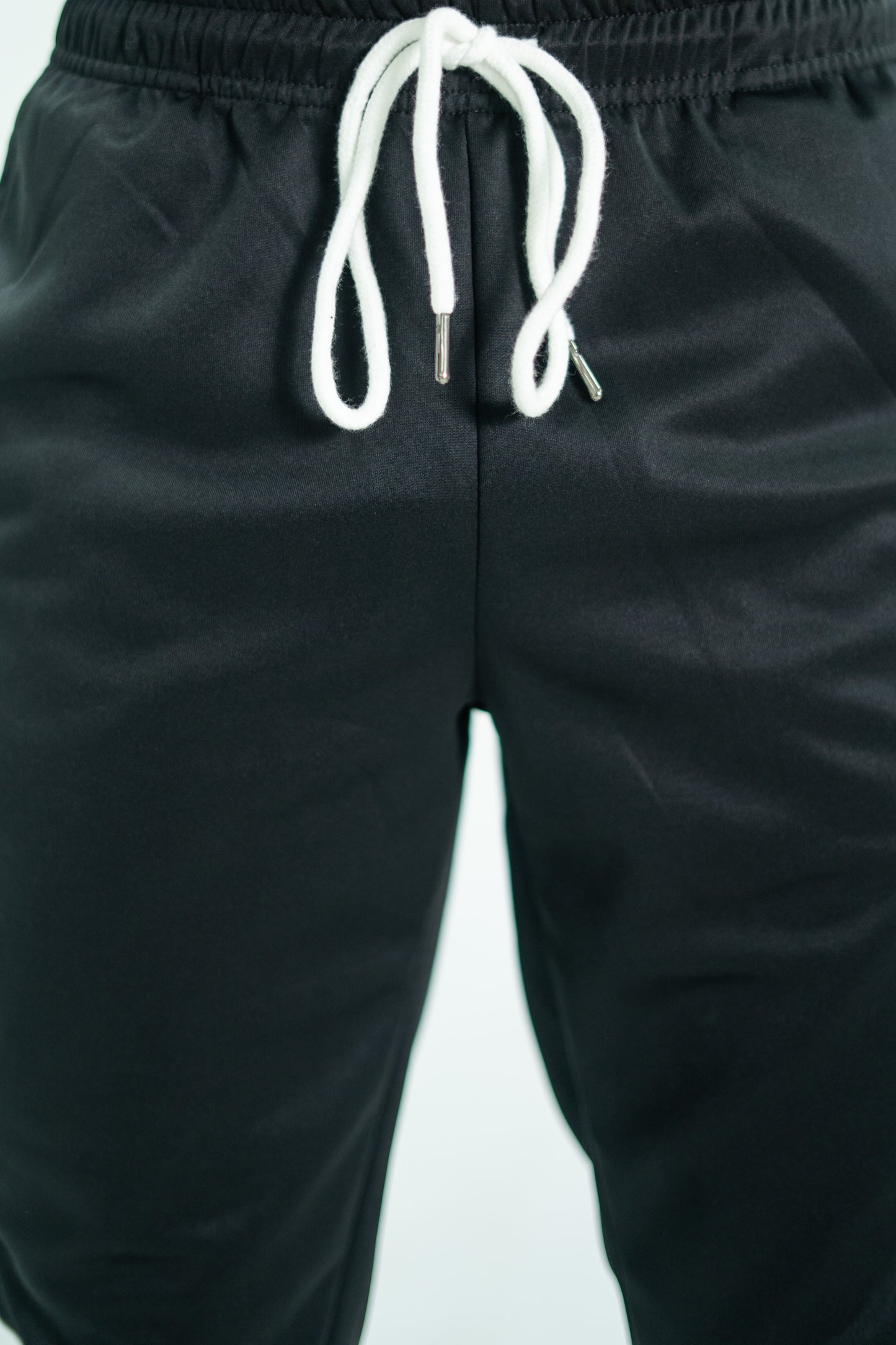 Black pants with a white drawstring on a light gray background

