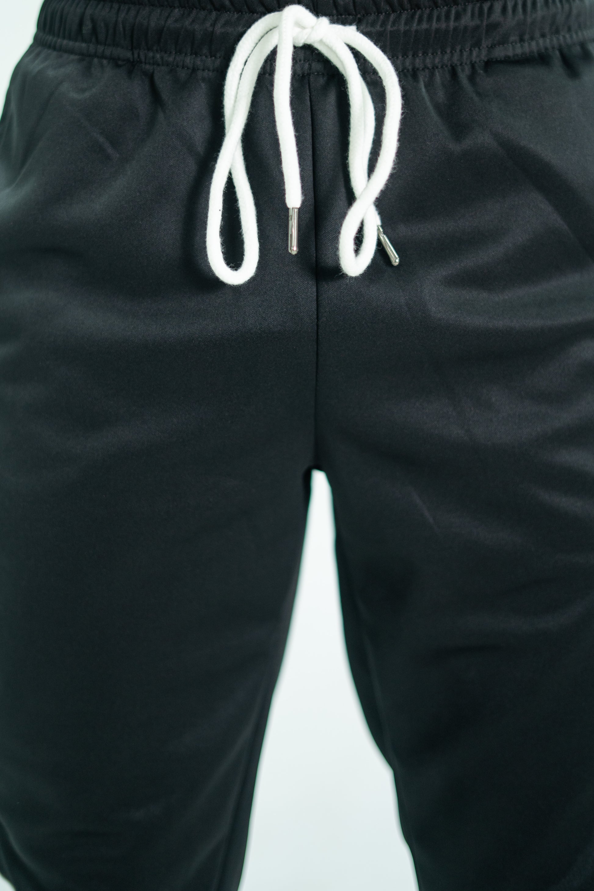 Black pants with a white drawstring on a light gray background

