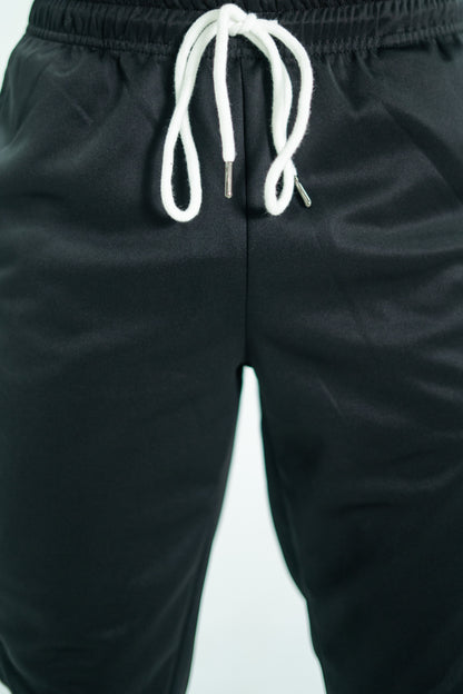 Black pants with a white drawstring on a light gray background

