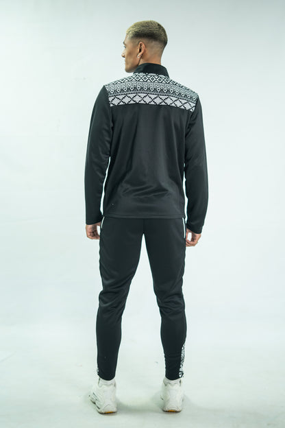 Person wearing a black tracksuit with a patterned chest area on a white background

