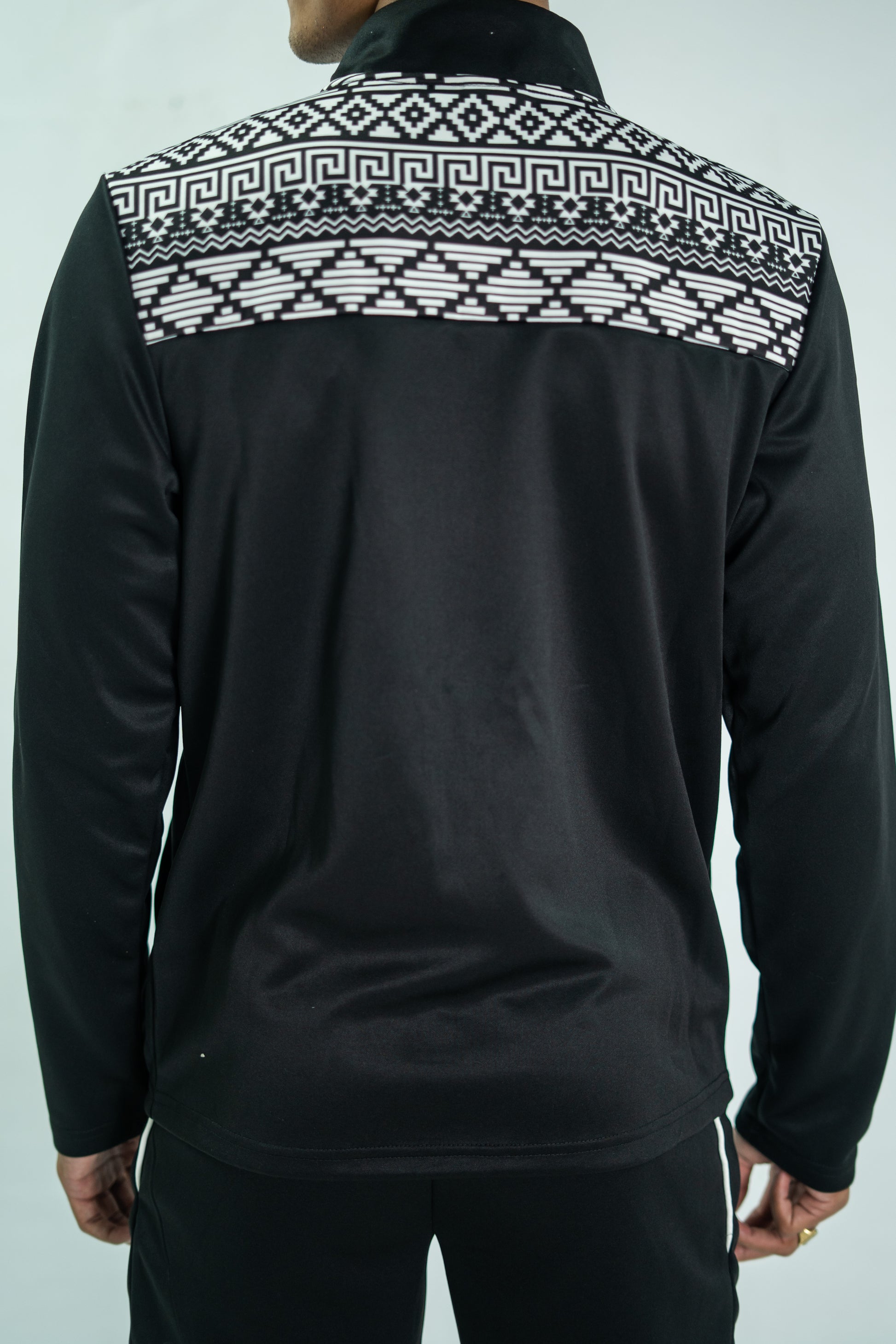 Black jacket with white geometric pattern on the back against a light gray background

