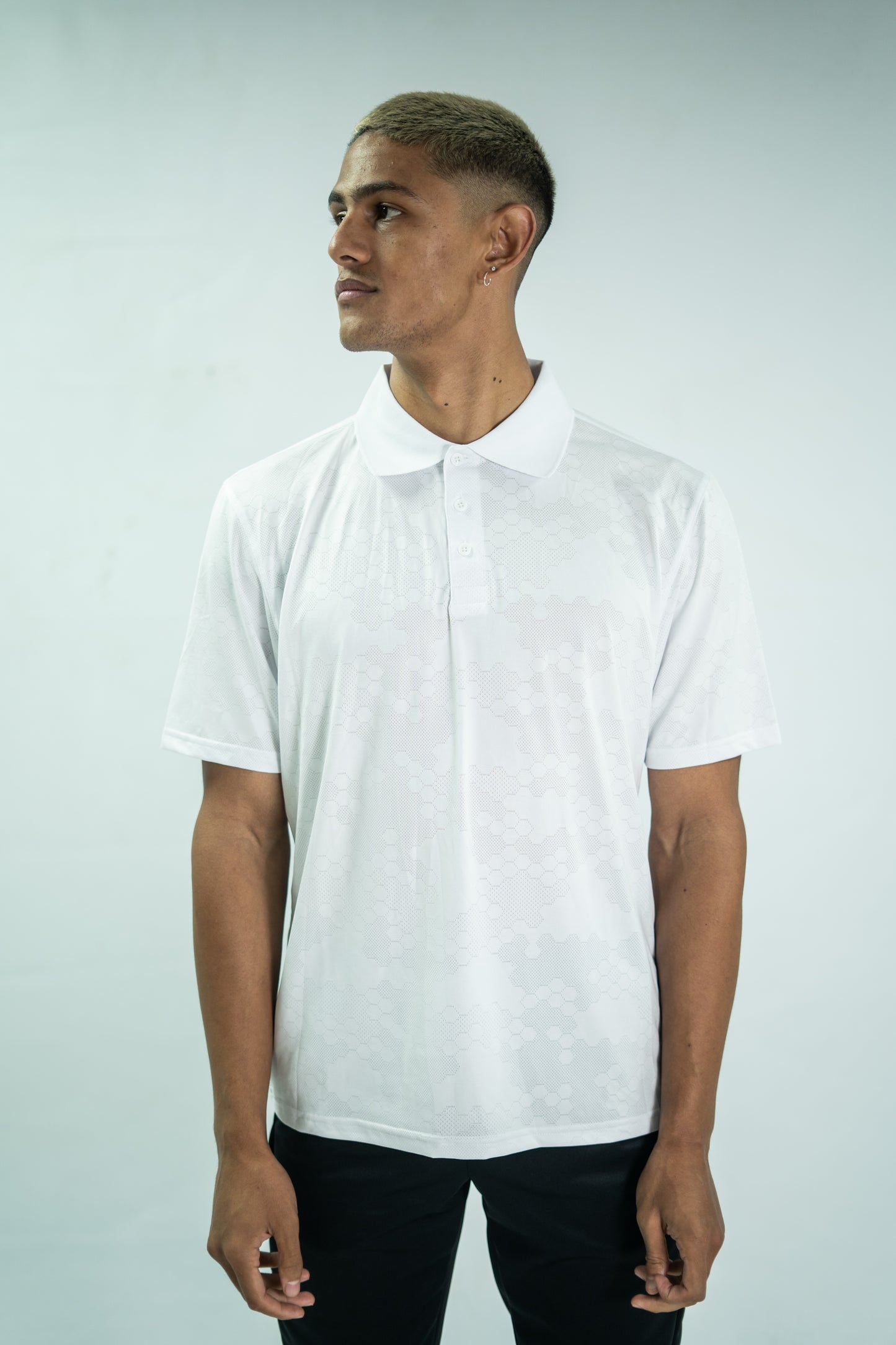 Man wearing a white polo shirt against a light gray background

