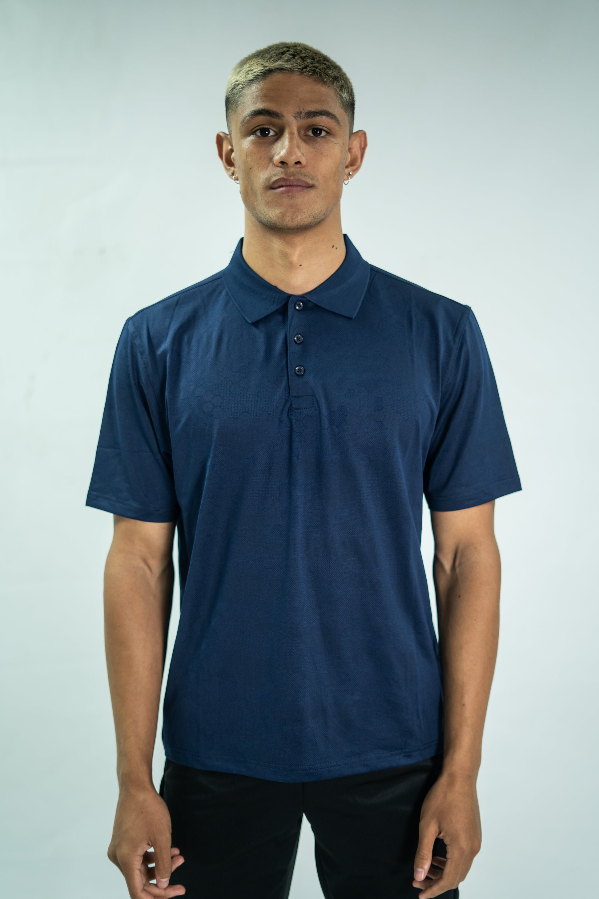 Man wearing a navy blue polo shirt against a plain background

