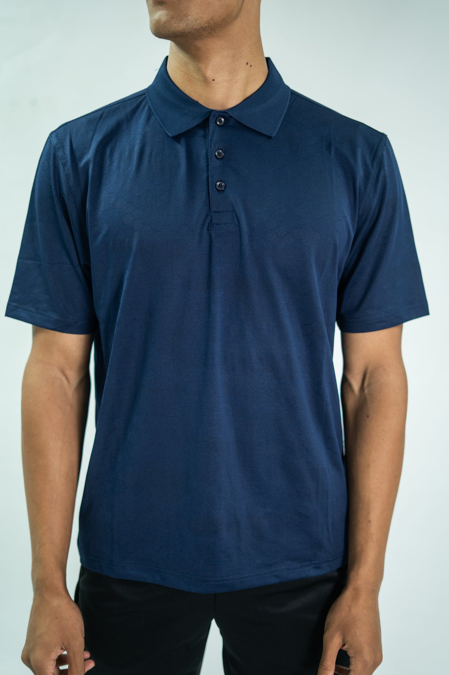 Person wearing a blue polo shirt against a plain background

