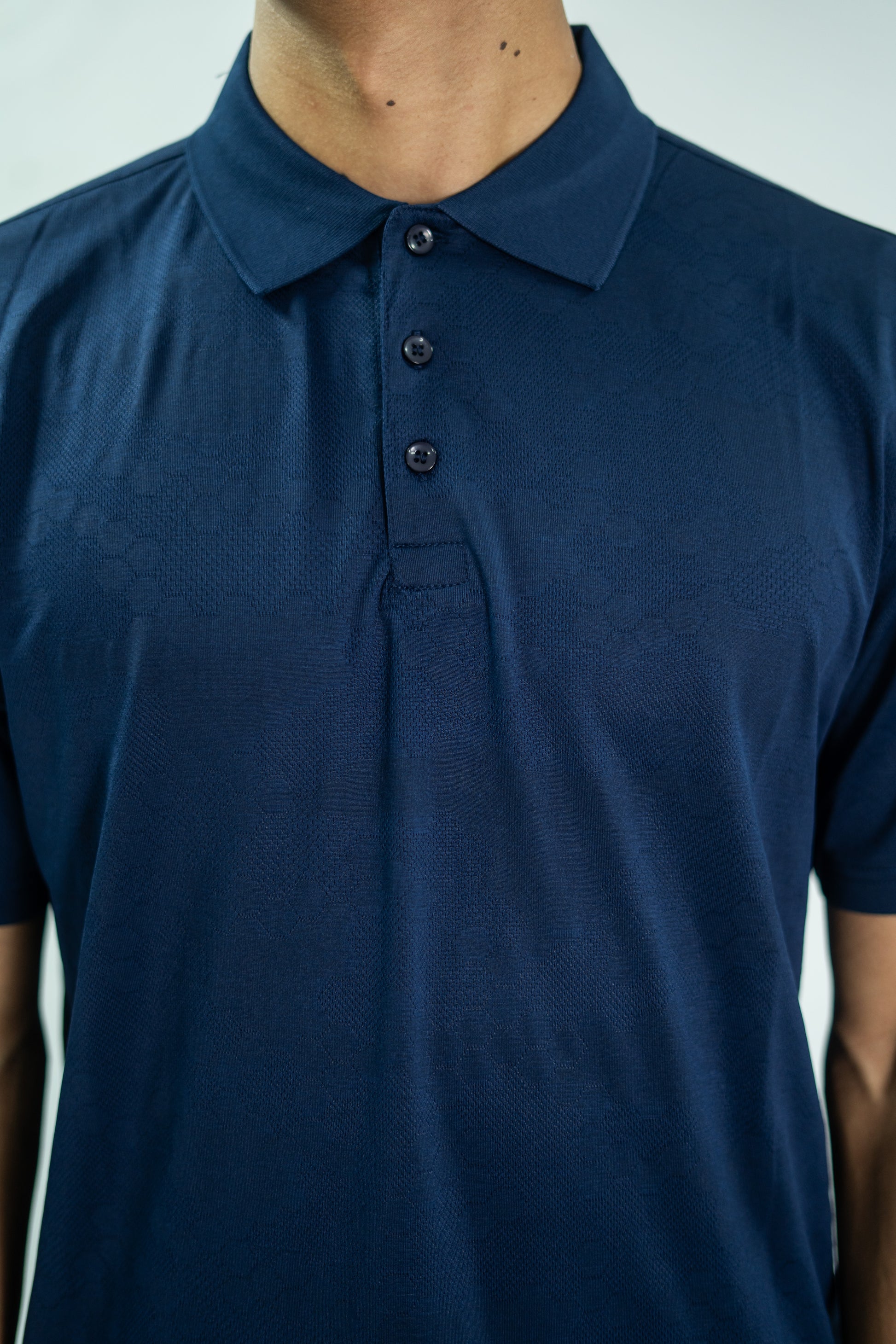 Navy blue polo shirt worn by a person on a light gray background

