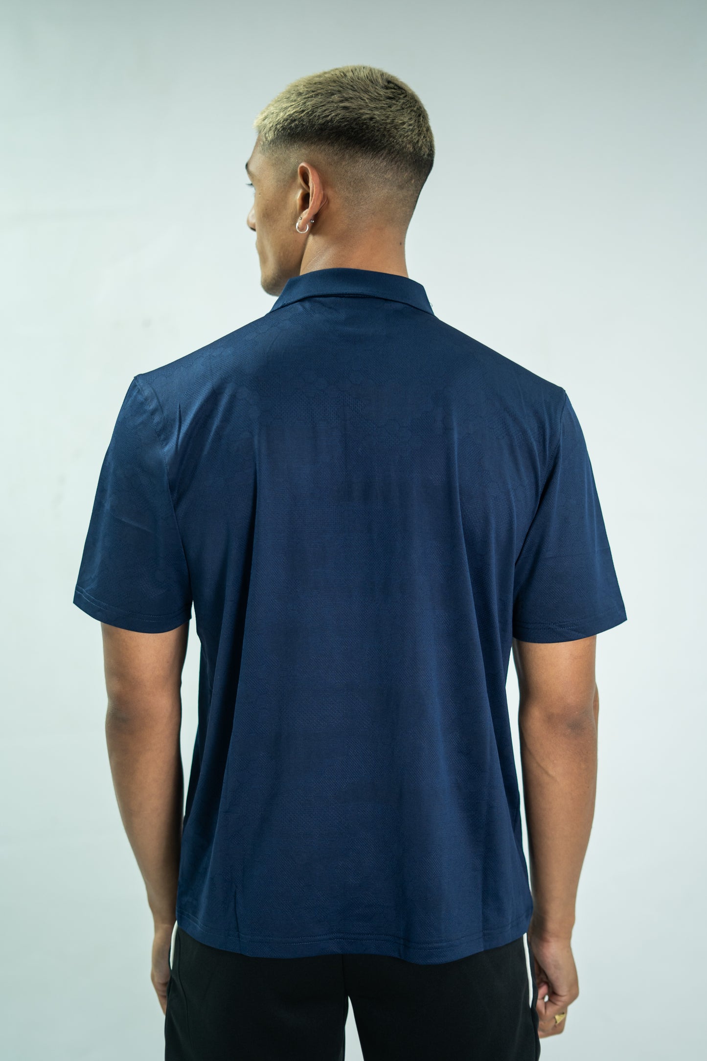 Person wearing a navy blue polo shirt on a plain background

