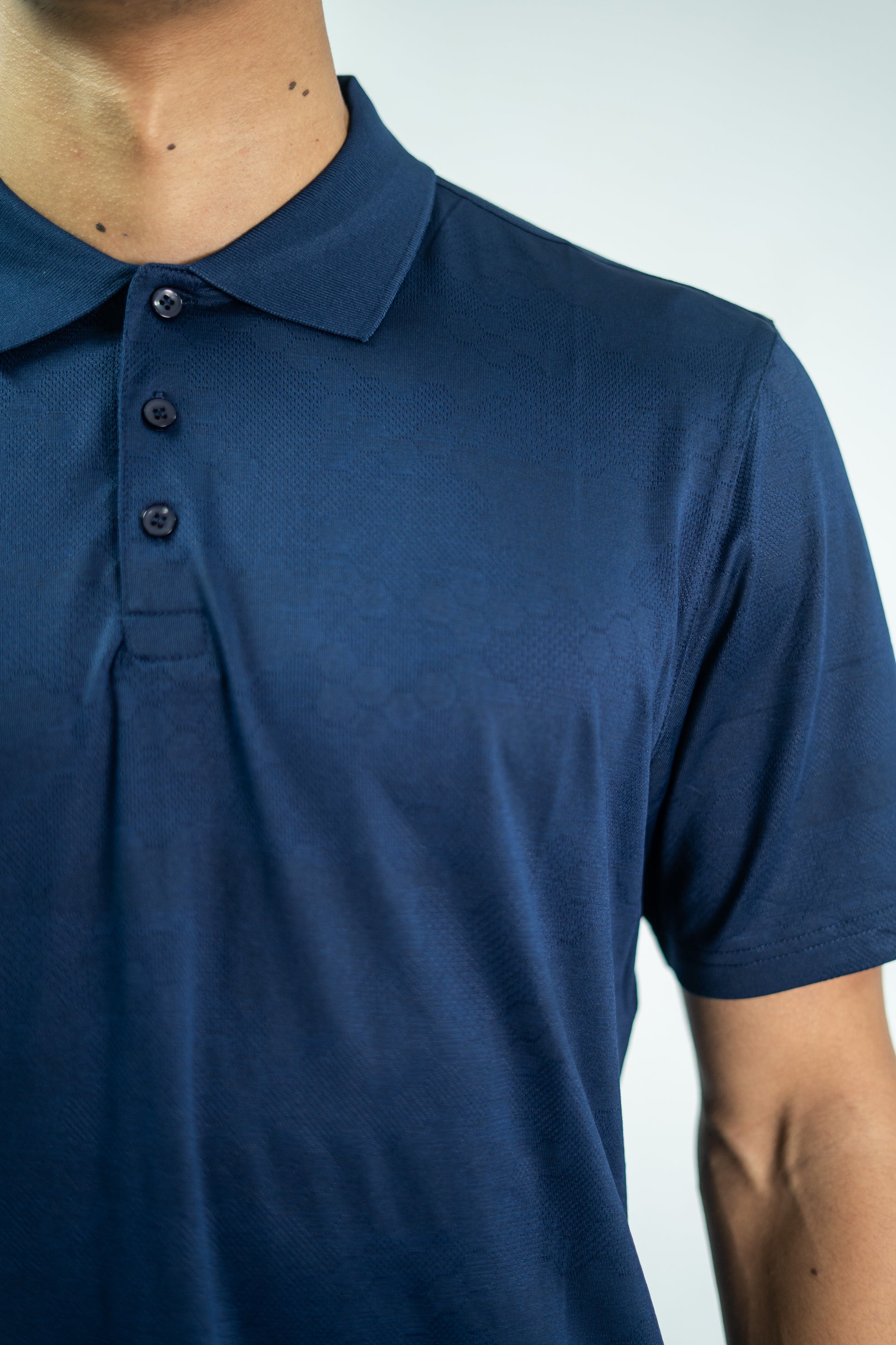 Navy blue polo shirt worn by a person on a light gray background


