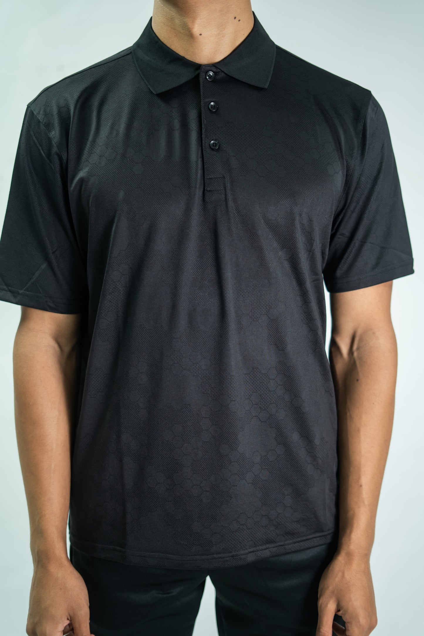 Person wearing a black polo shirt against a plain background

