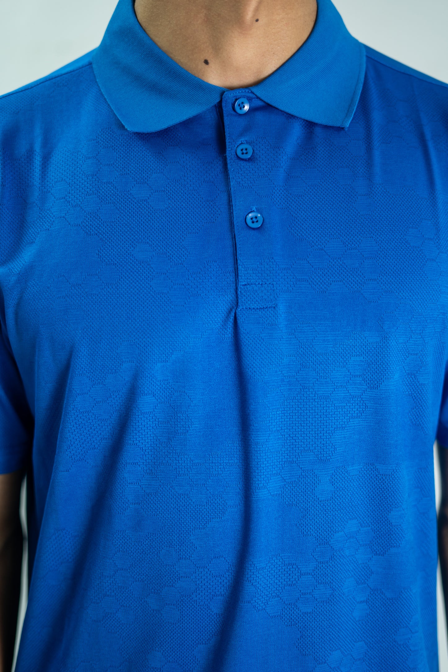 Blue polo shirt worn by a person against a neutral background

