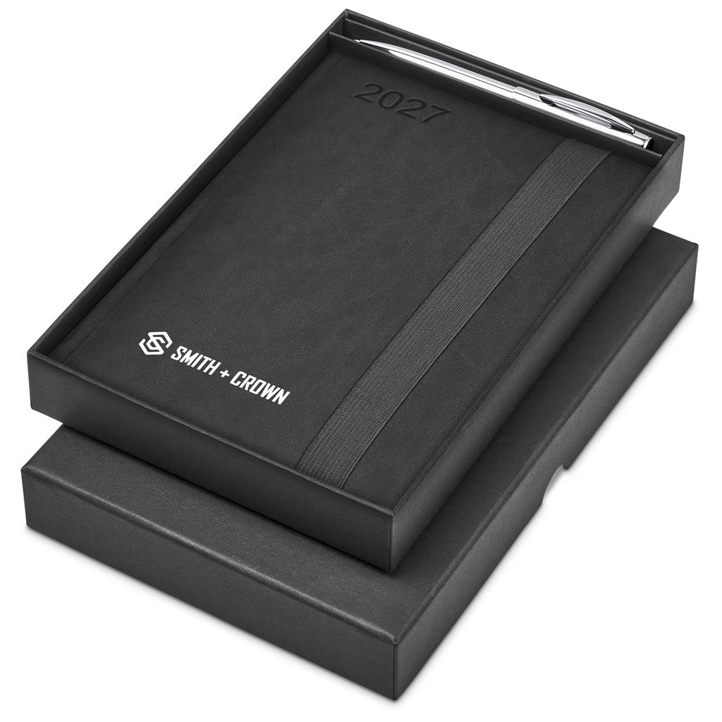 A black 2027 Smith + Crown leather-bound notebook with a silver pen, presented in a matching black gift box on a white background.

