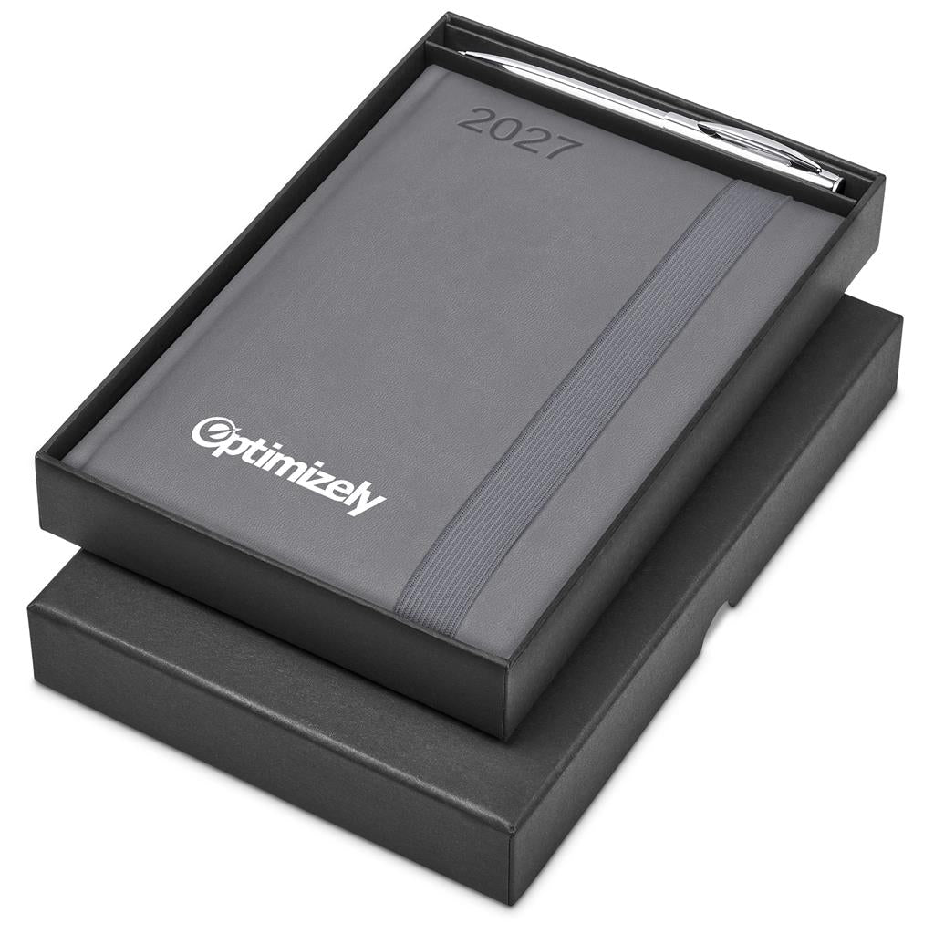 A black 2027 planner or calendar presented in an open black gift box, with a silver pen resting in the top slot. The front cover shows the Optimizely brand name in white.

