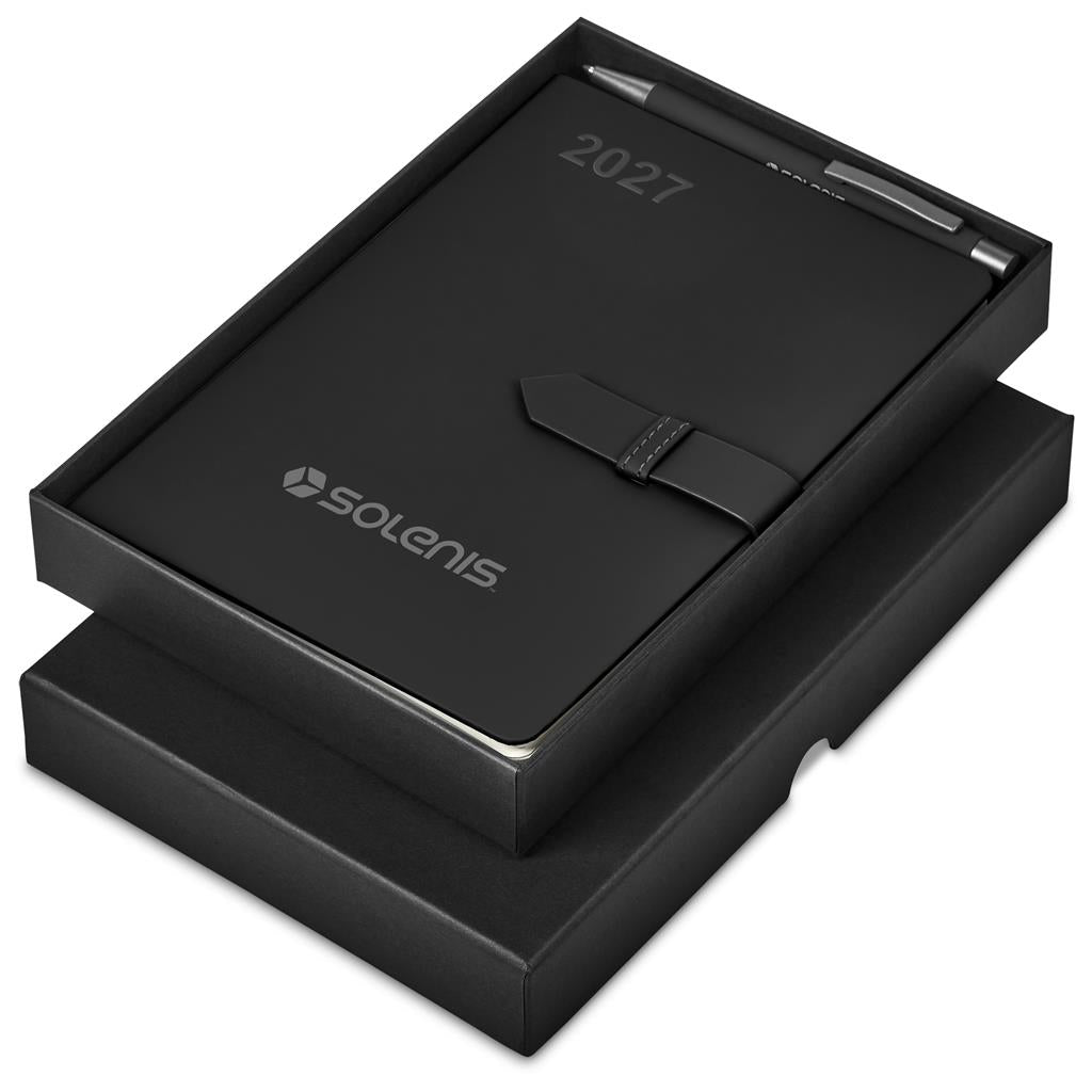 A black 2027 Solenis leather-bound notebook with a pen, presented in its open black gift box on a white background.

