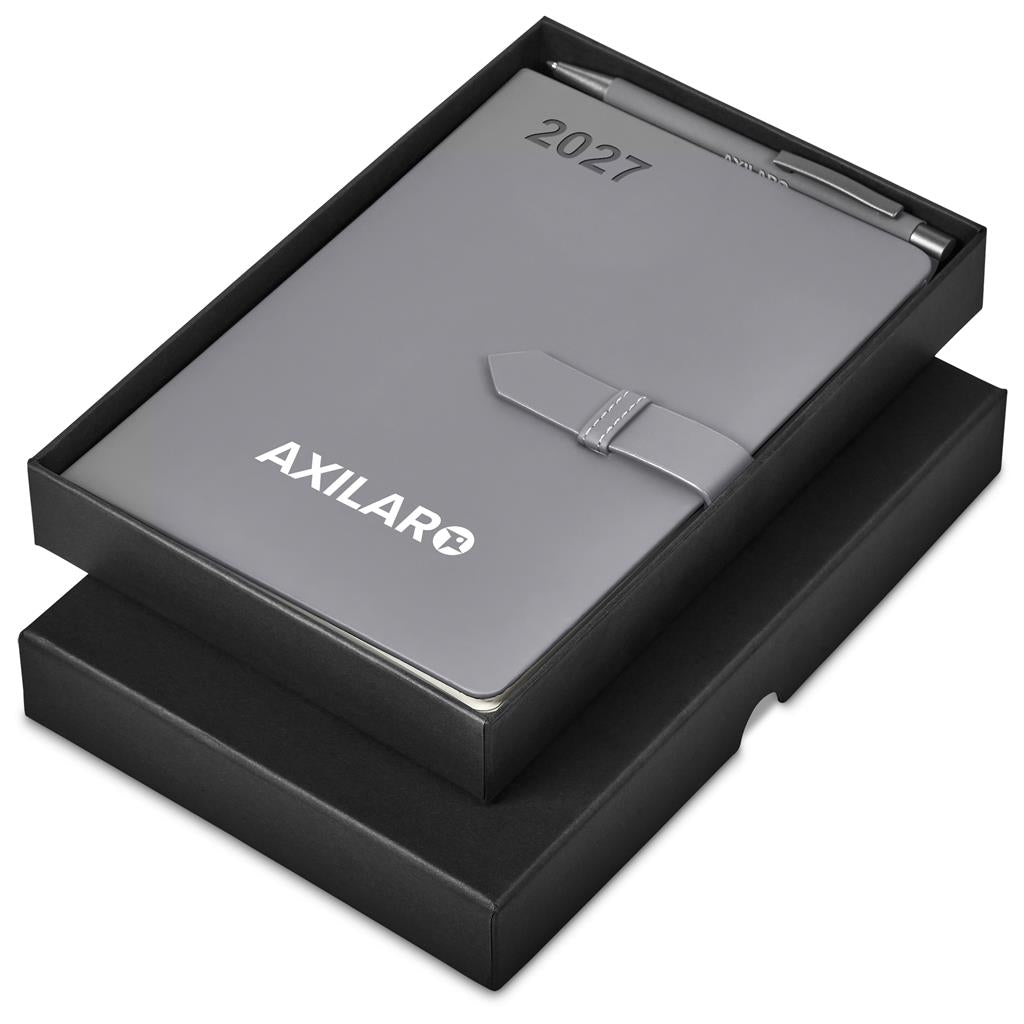 A silver metallic 2027 leather-bound journal with a pen, presented in an open black gift box. The journal features the brand name 'AXILAR' and the year '2027' printed on the cover.

