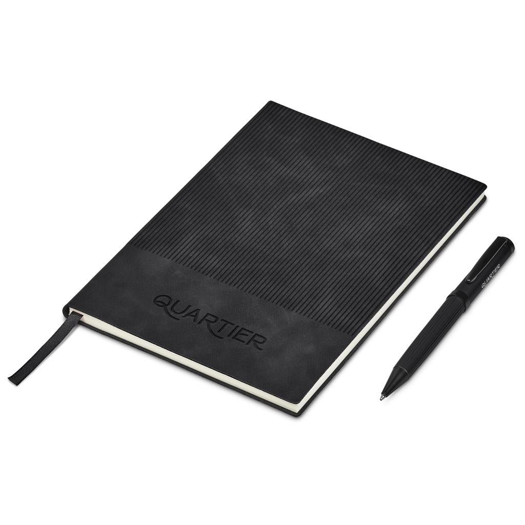 Black notebook with textured cover and pen on a white background, featuring the brand 'Quartier'.

