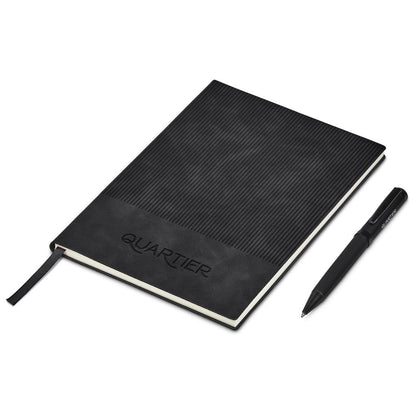 Black notebook with textured cover and pen on a white background, featuring the brand 'Quartier'.

