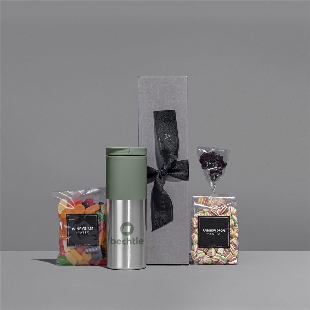 Green tumbler with a black bow and two candy packages on a gray background

