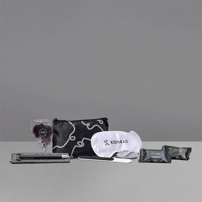 Travel kit with pouch, eye mask, and other items on a gray background

